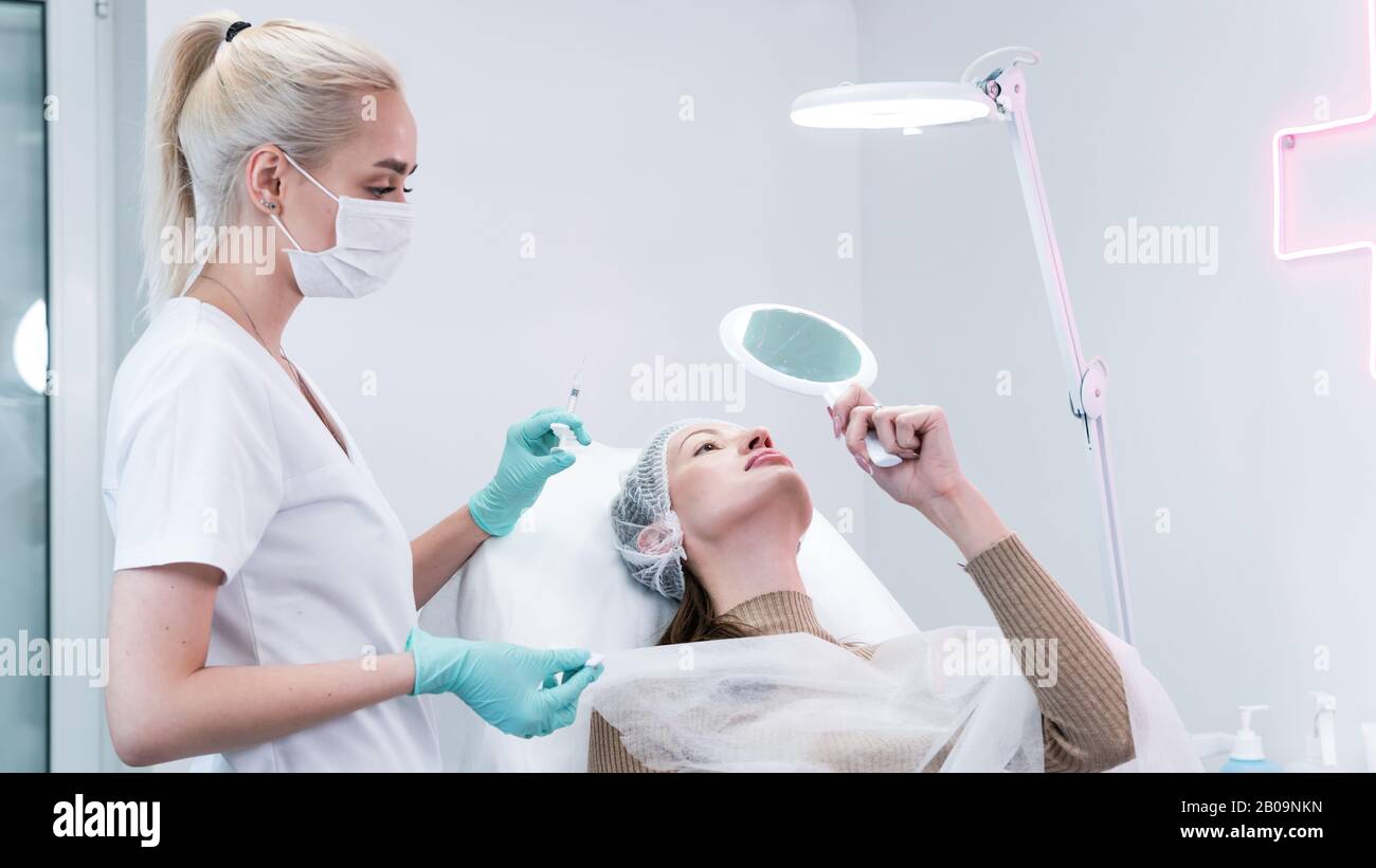 The young beautician doctor preparing to making injection in female lips. The doctor cosmetologist makes lip augmentation procedure. Concept of beauty Stock Photo