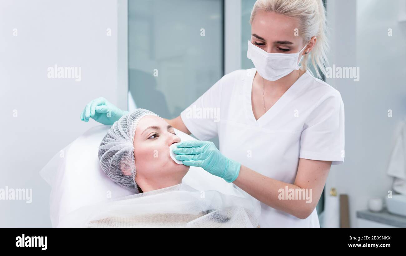 The young beautician doctor preparing to making injection in female lips. The doctor cosmetologist makes lip augmentation procedure. Concept of beauty Stock Photo