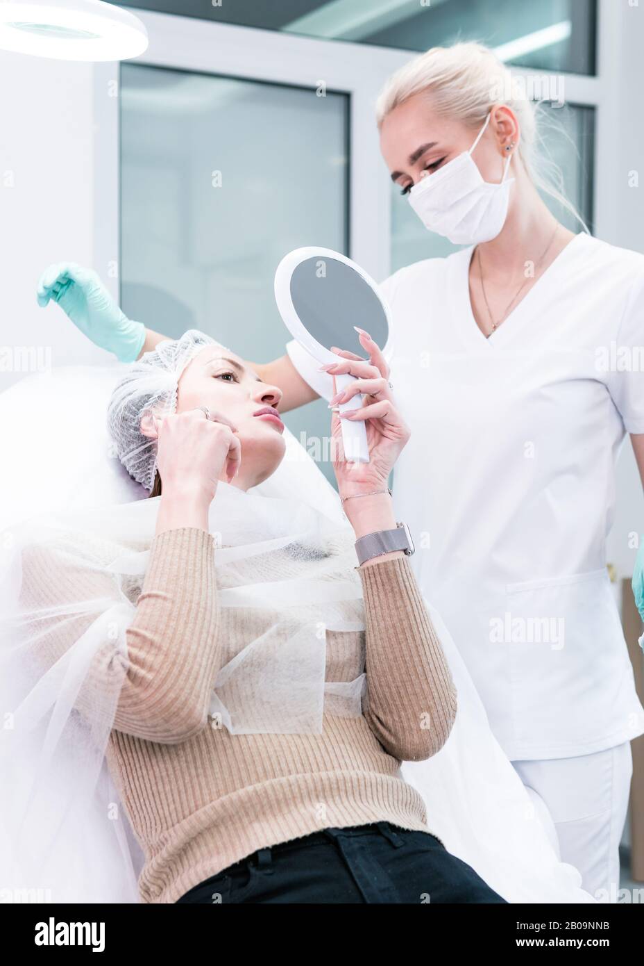 The young beautician doctor preparing to making injection in female lips. The doctor cosmetologist makes lip augmentation procedure. Concept of beauty Stock Photo