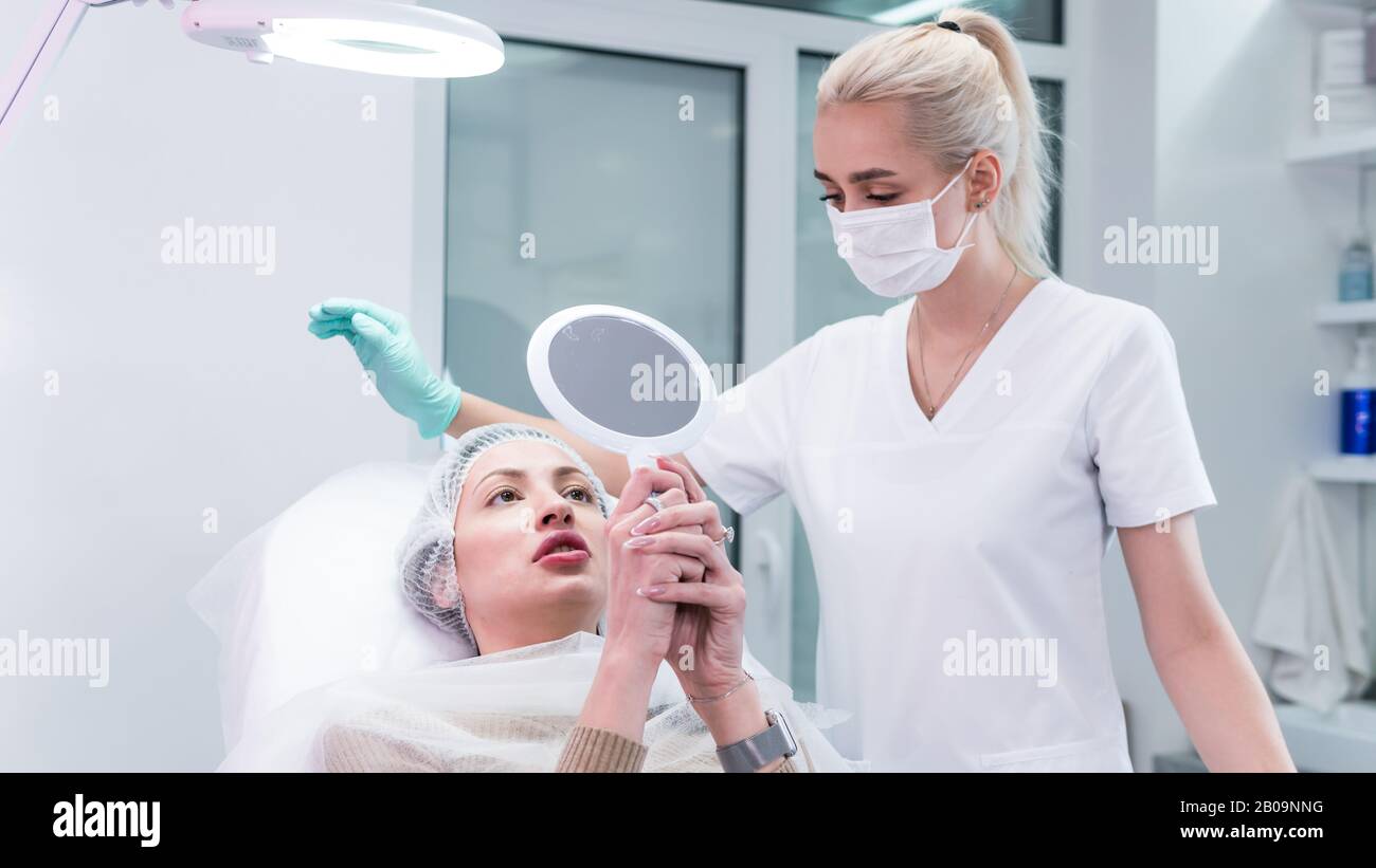 The young beautician doctor preparing to making injection in female lips. The doctor cosmetologist makes lip augmentation procedure. Concept of beauty Stock Photo