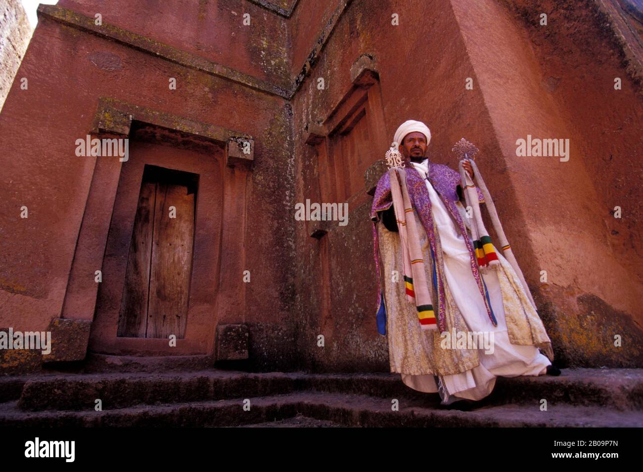 ETHIOPIA, LALIBELA, UNESCO WORLD HERITAGE SITE,  CHURCH CARVED INTO ROCK, CROSS CHURCH, PRIEST WITH CROSS Stock Photo