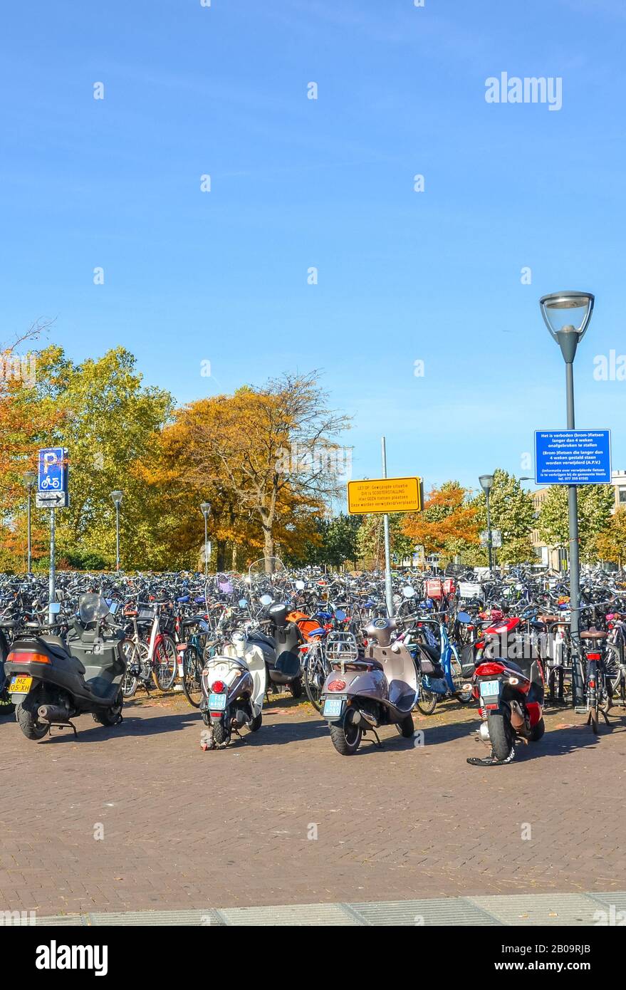 Venlo, Limburg, Netherlands - October 13, 2018: Rows of parked bicycles and motorcycles in the Dutch city close to the main train station. City biking. Eco-friendly means of transport. Vertical photo. Stock Photo