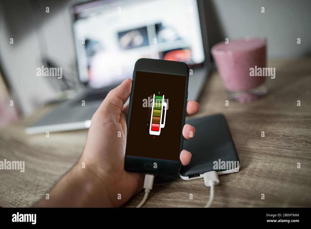 Man holding mobile phone in his hand that is charging with power bank