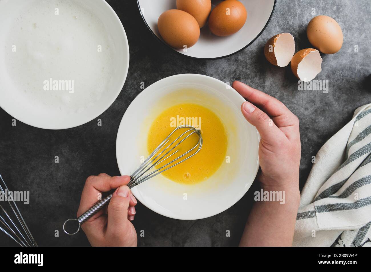 Woman's hands whisk eggs in bow. Cooking omlette for breakfast. Top