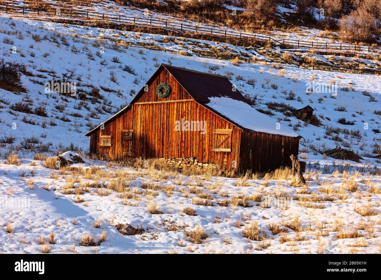 A wooden barn catches the last light of day in the foothills of the San Juan Mountains in Telluride, Colorado Stock Photo