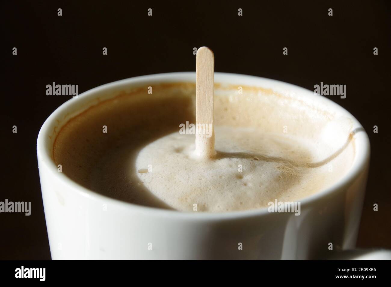 Creamy coffee, with stirring stick standing up in it Stock Photo