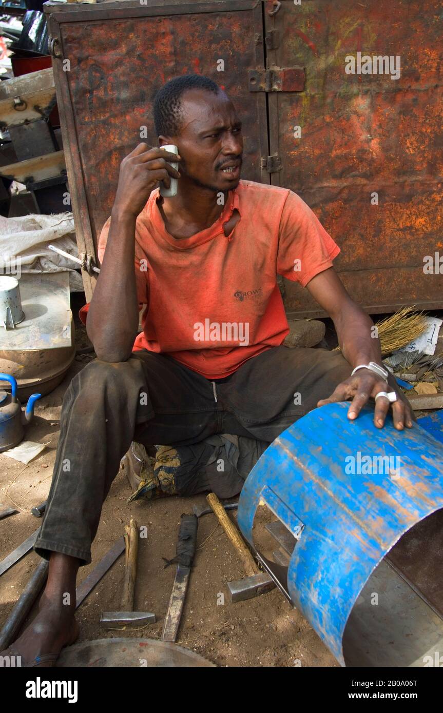 MALI, BAMAKO, RECYCLE MARKET, SCRAP METAL WORKER ON CELL PHONE Stock Photo