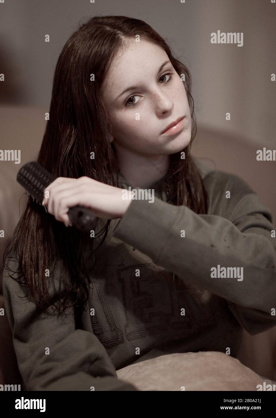 A teenage girl with green eyes, fair skin, and freckles, wearing a green  hoodie, brushing her wet, dark brown hair after washing it Stock Photo -  Alamy