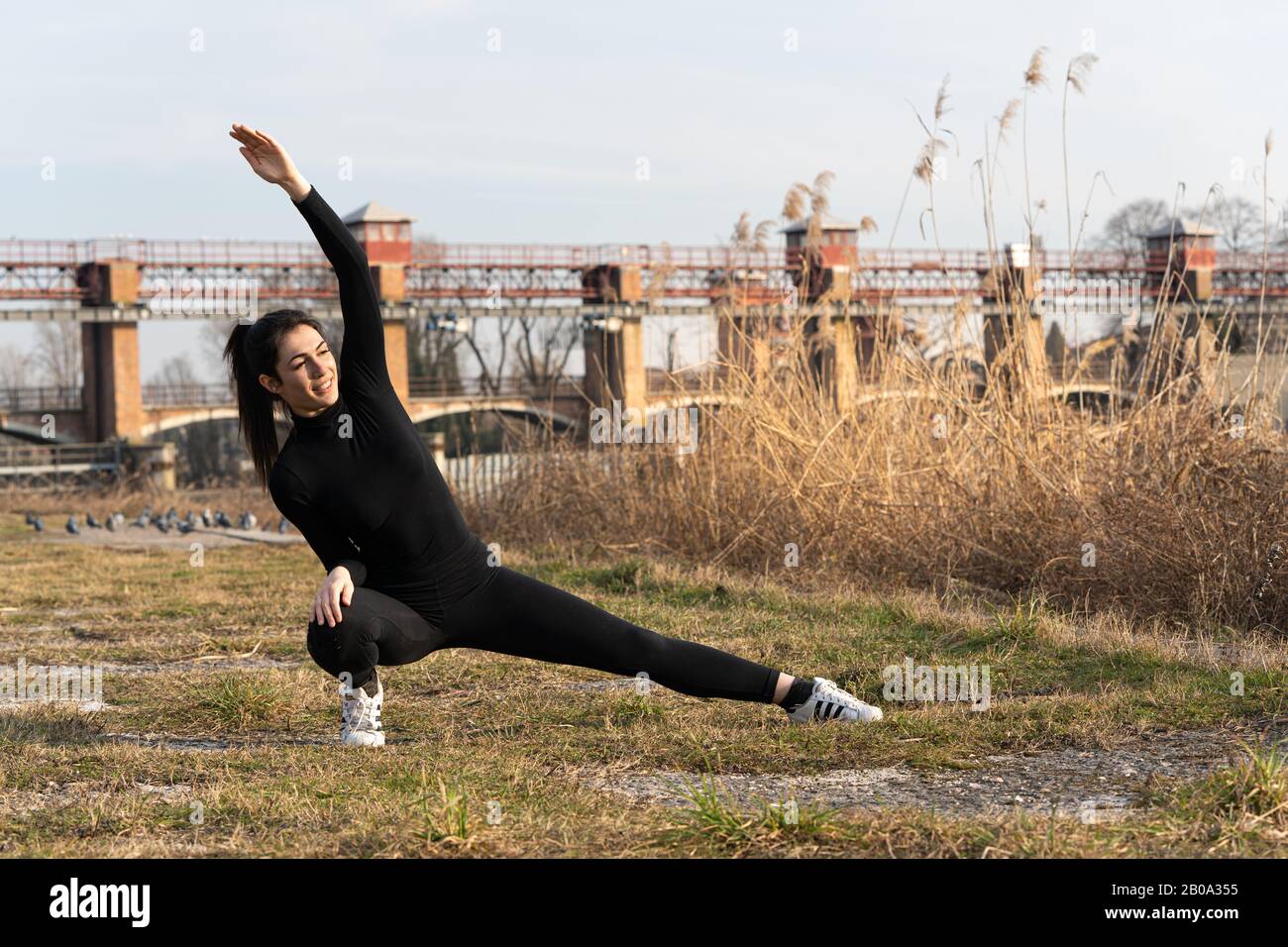 Portrait of sports girl doing yoga stretching exercise on the riverside Stock Photo