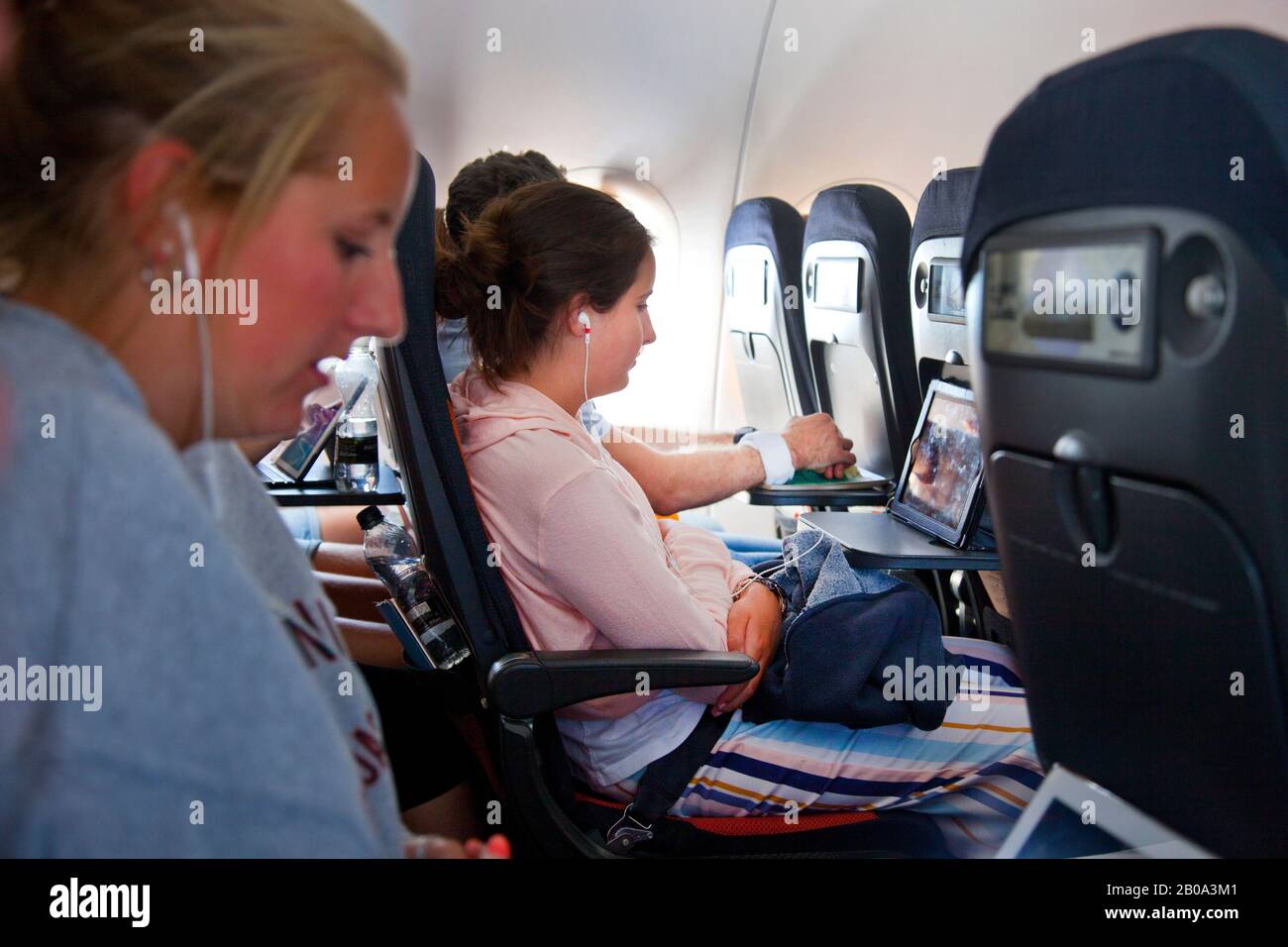 Teenage girls ( both model released ) sitting on Easyjet aircraft wearing  headphones and watching portable media ( ipad ) during flight Stock Photo -  Alamy