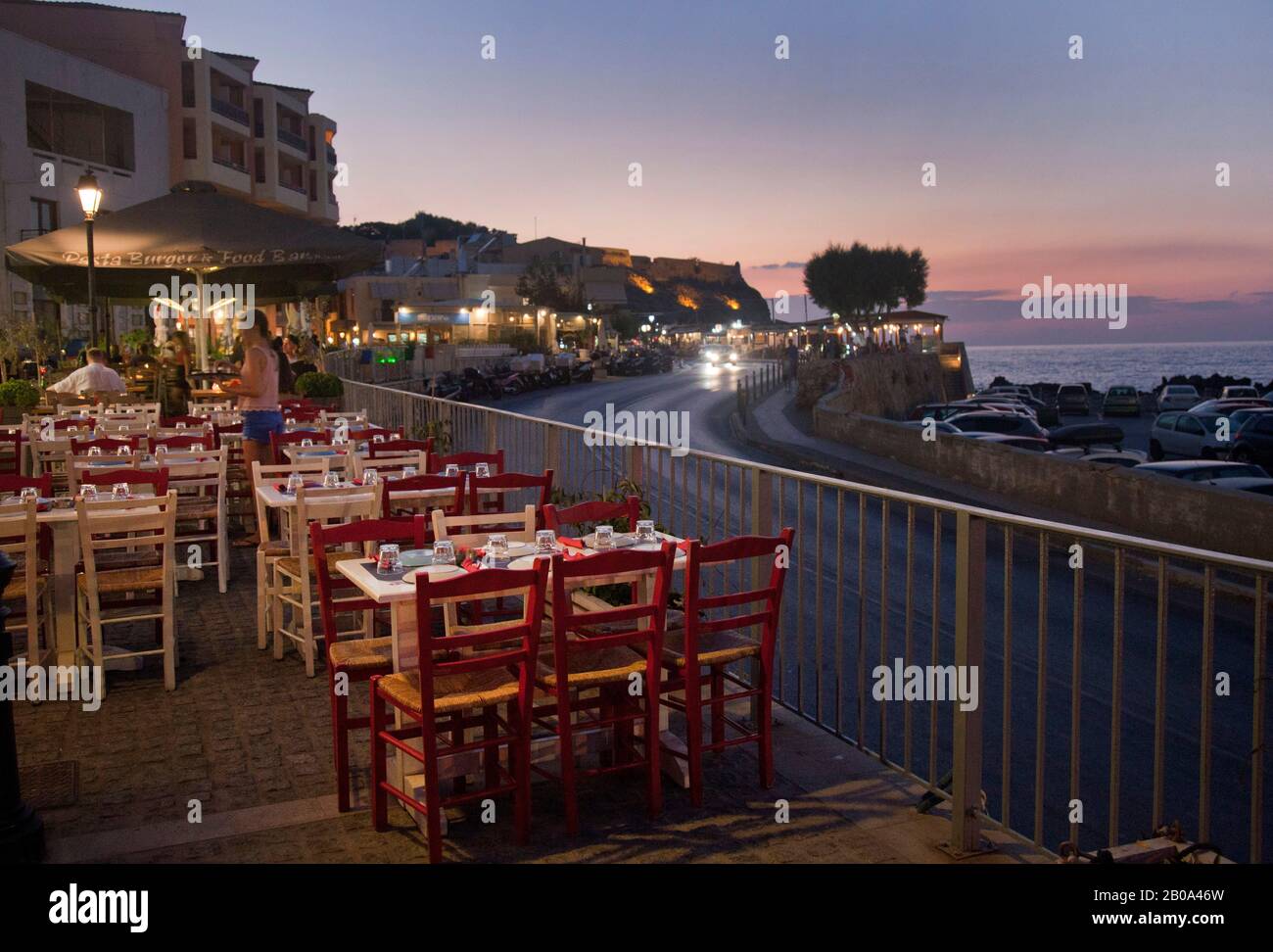 Tables outside of a taverna ( restaurant ) near the Venetian harbour  in the old town of Rethymno ( Rethimno ). The city is located on the north coast Stock Photo