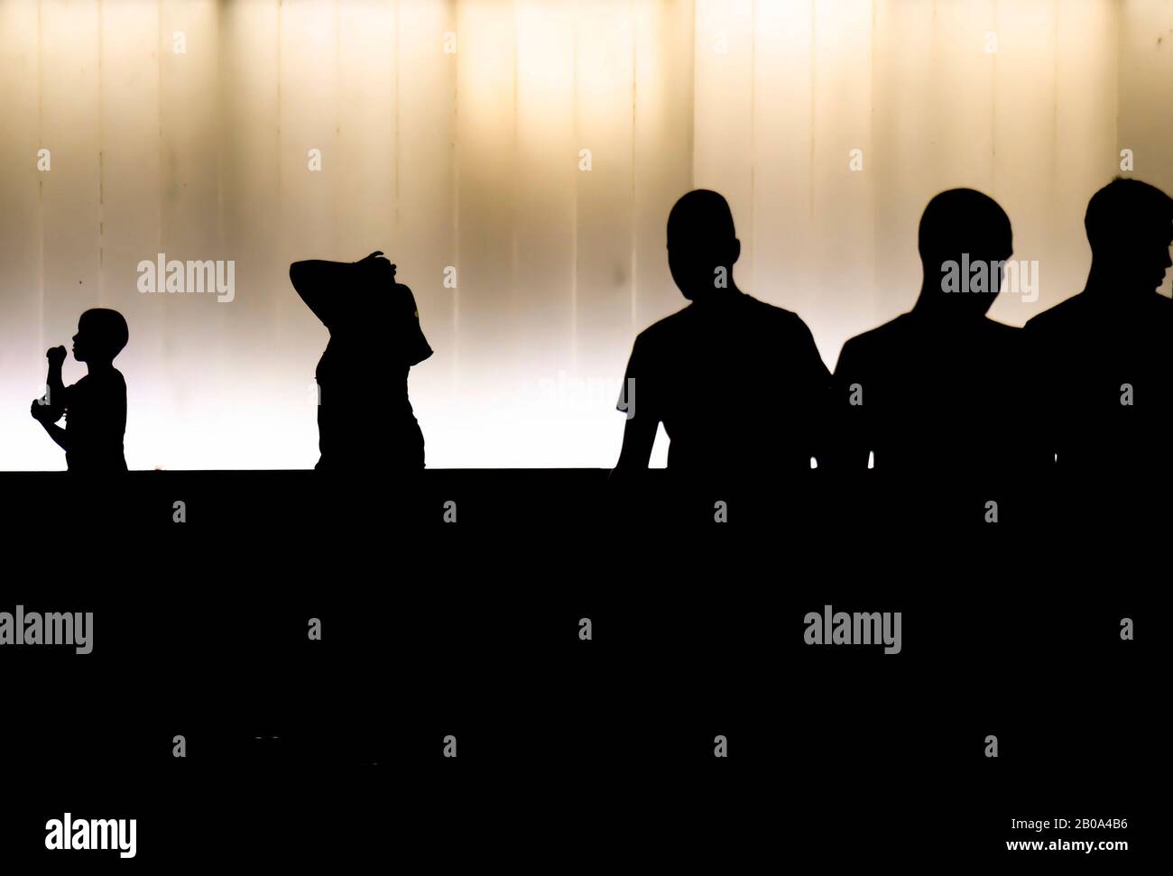 Silhouettes of young boys walking in the summer night , in front of modern building, in high contrast black and white Stock Photo