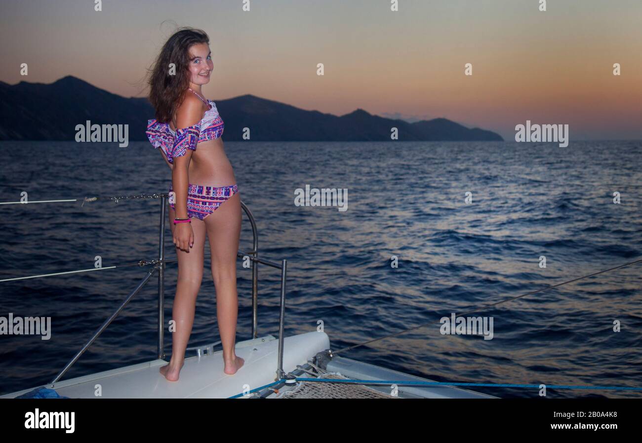 A teenage girl ( model released ) watches the sunset ,from the bow of a yacht, in Crete on the northern coastline between Bali and Panormos. August 20 Stock Photo