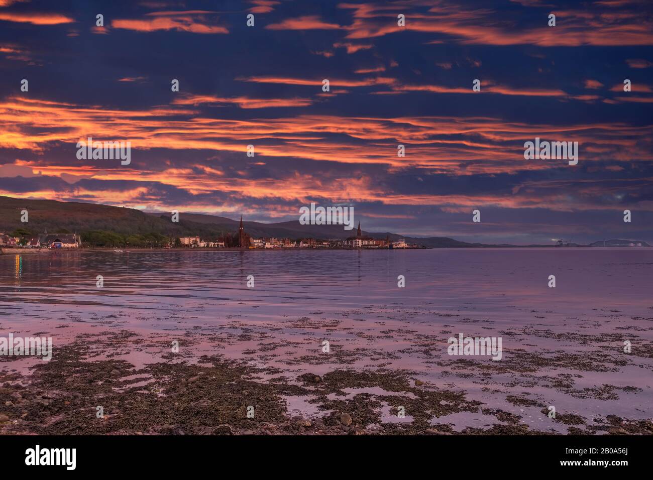 Largs Looking South into the town at sunset with the sunset reflections on the town seafront. A good holiday touristic image. Stock Photo