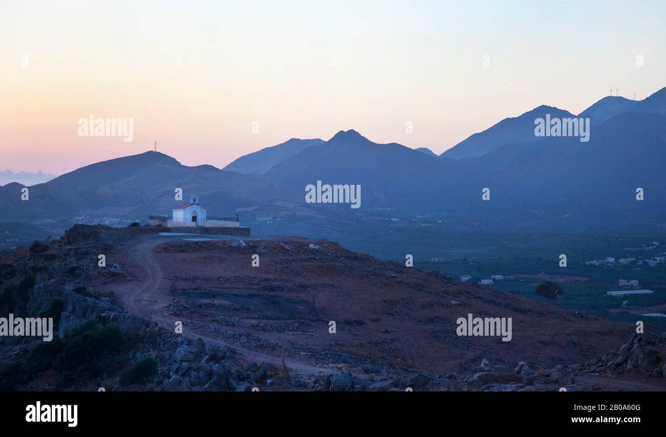 Sunrise over a small chapel on top of hills that overlook Panormos ( not shown ) in Crete with mountains in the background Stock Photo
