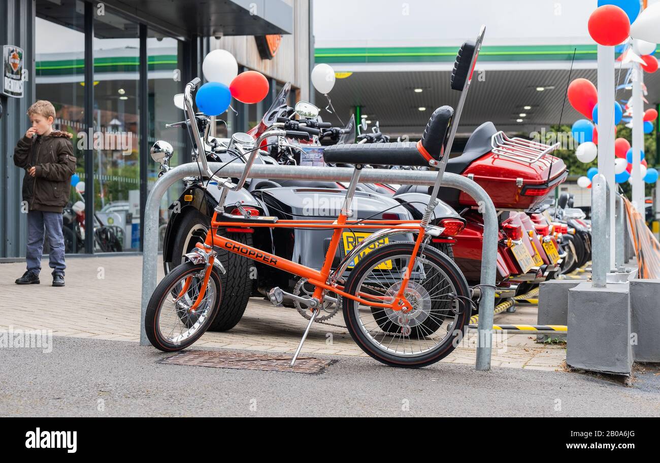 Boy parks his Raleigh Chopper 3 gear bicycle at Harley-Davidson Reading Berkshire England Stock Photo