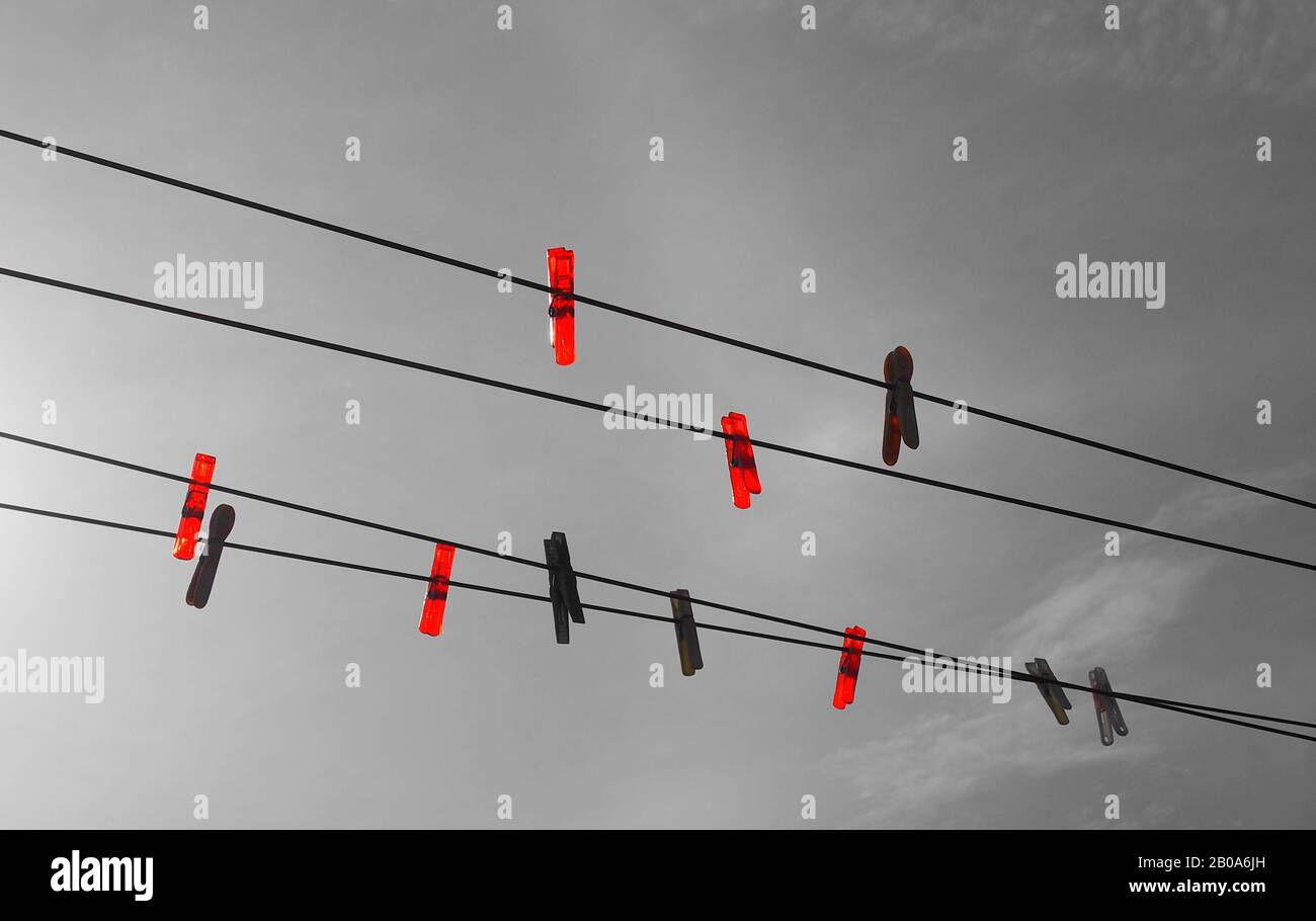 Bright red plastic pegs on a clothes line against a grey sky Stock Photo