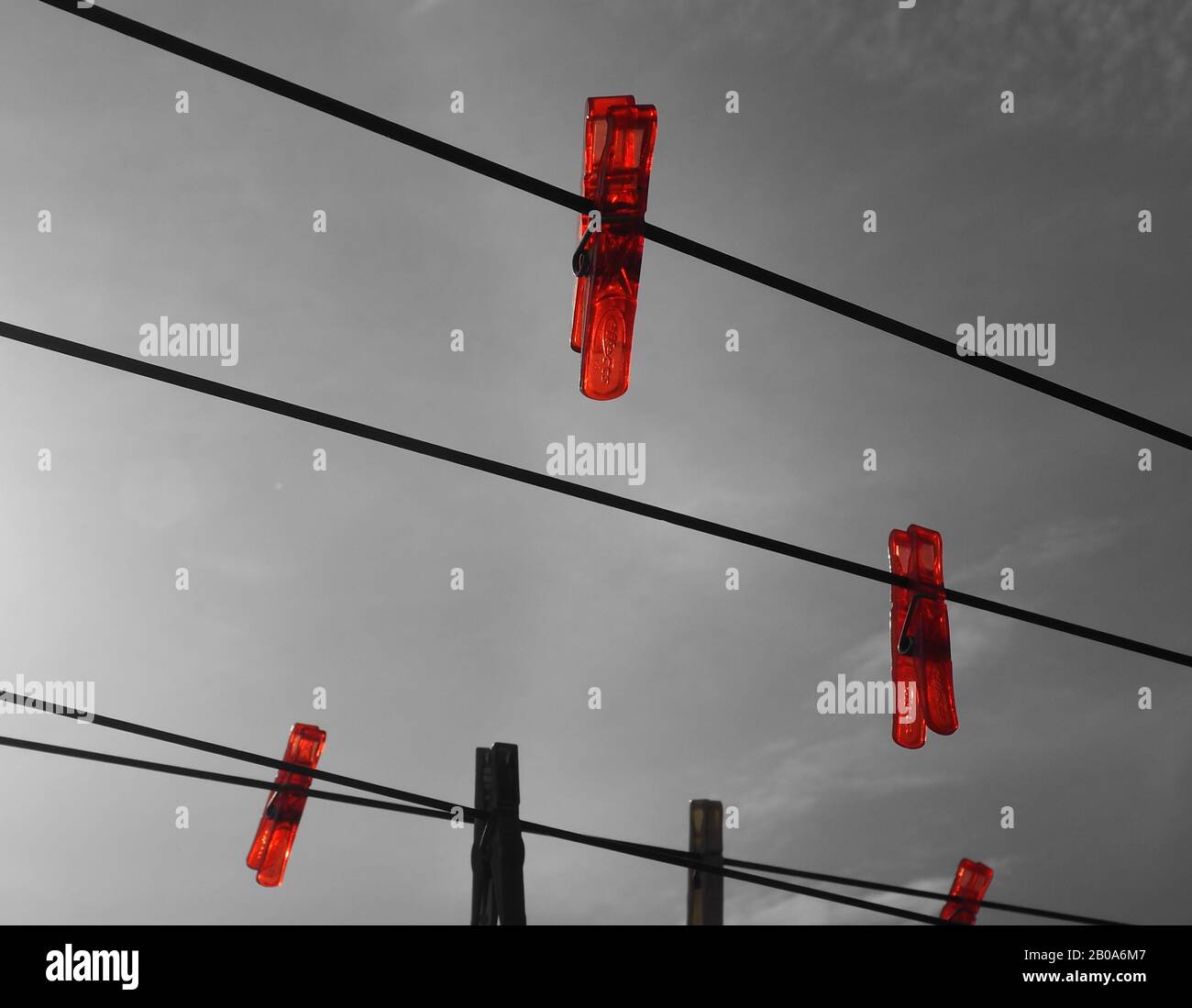 Bright red plastic pegs on a clothes line against a grey sky Stock Photo