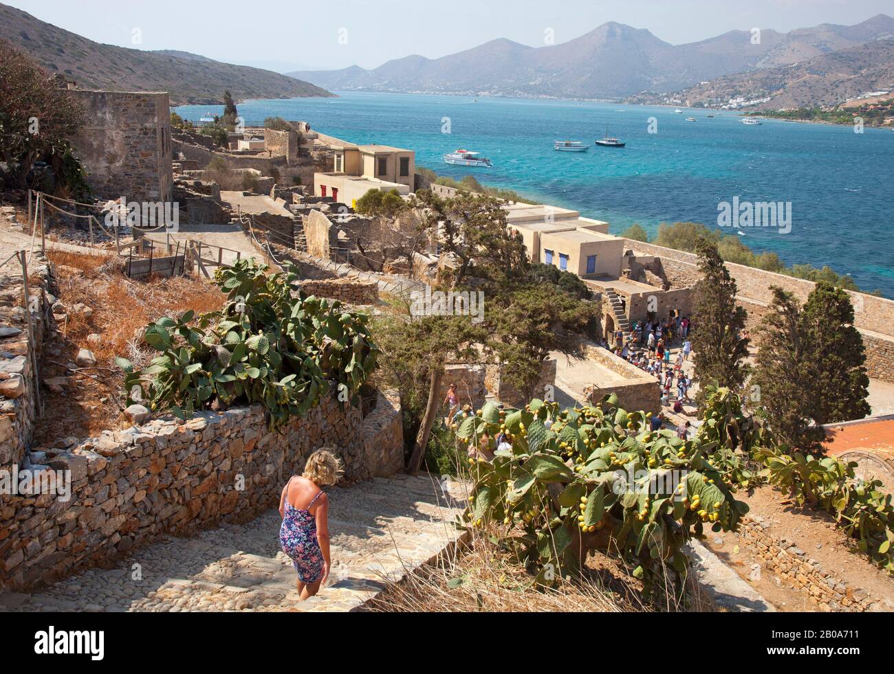 A tourist explores ruined buildings on the island of Spinalonga  ( also known as Kalydon ) in  Crete. The island was used as a leper colony Stock Photo