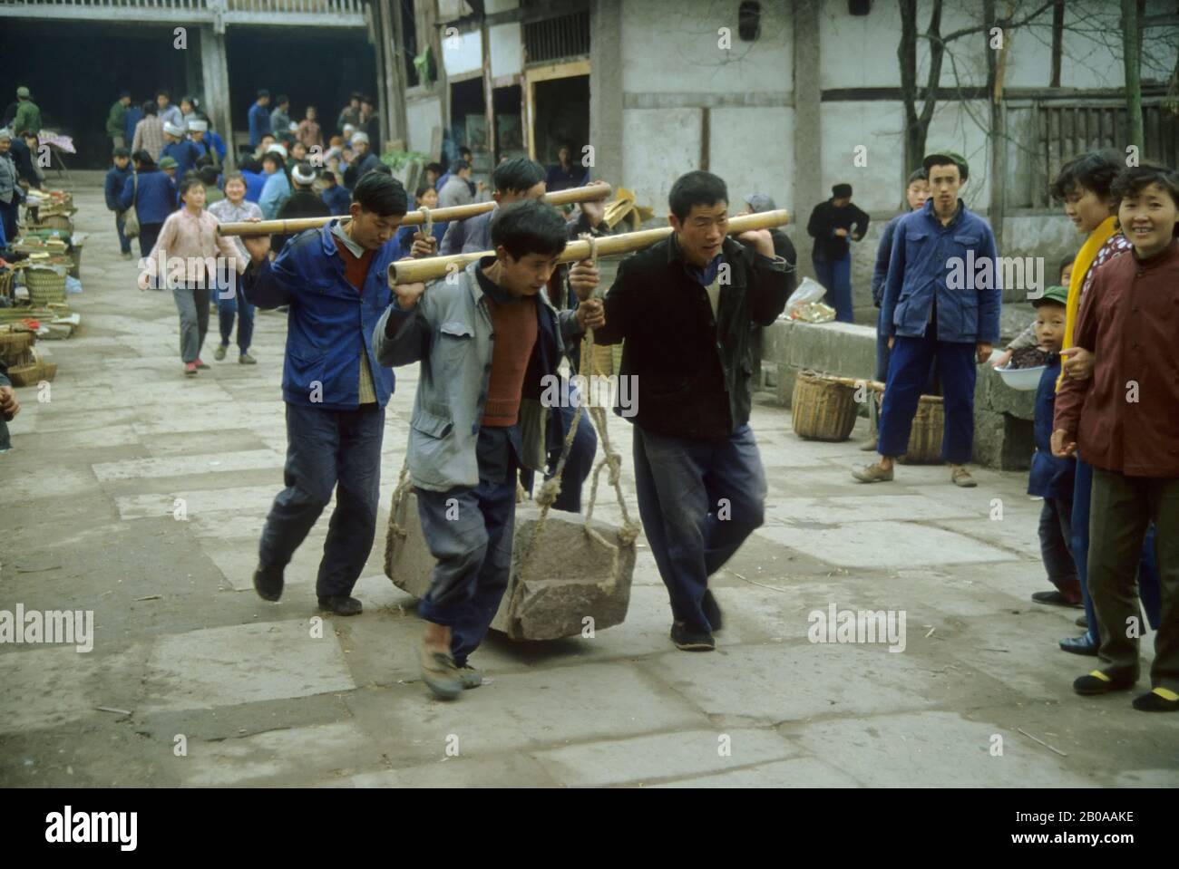 CHINA, DAZU, MEN TRANSPORTING A HEAVY STONE WITH BAMBOO POLES Stock Photo