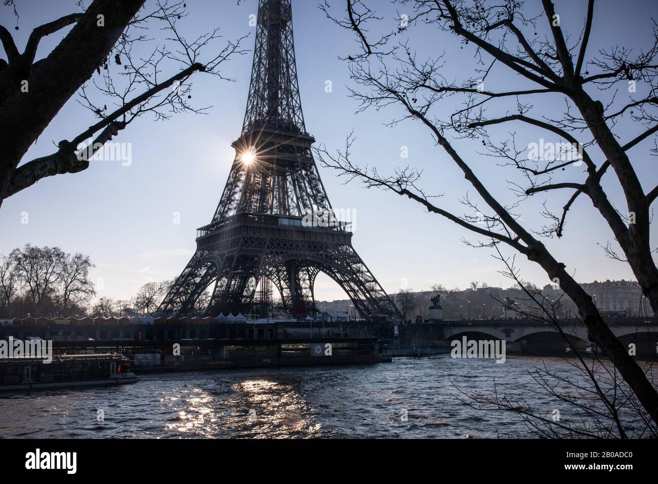 The sun rises behind the Eiffel Tower and Seine River in Paris Stock Photo