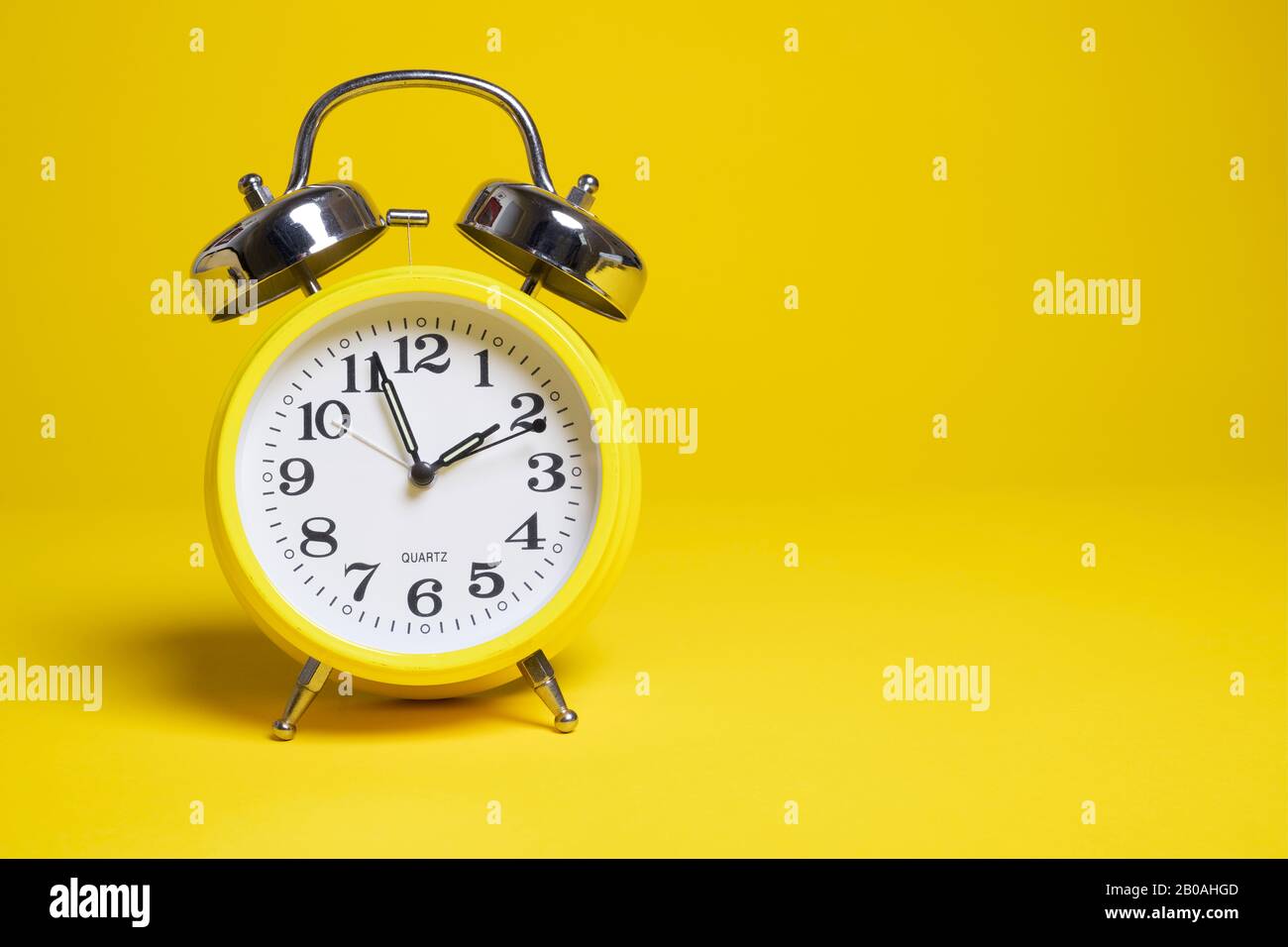 A yellow alarm clock on a yellow background Stock Photo