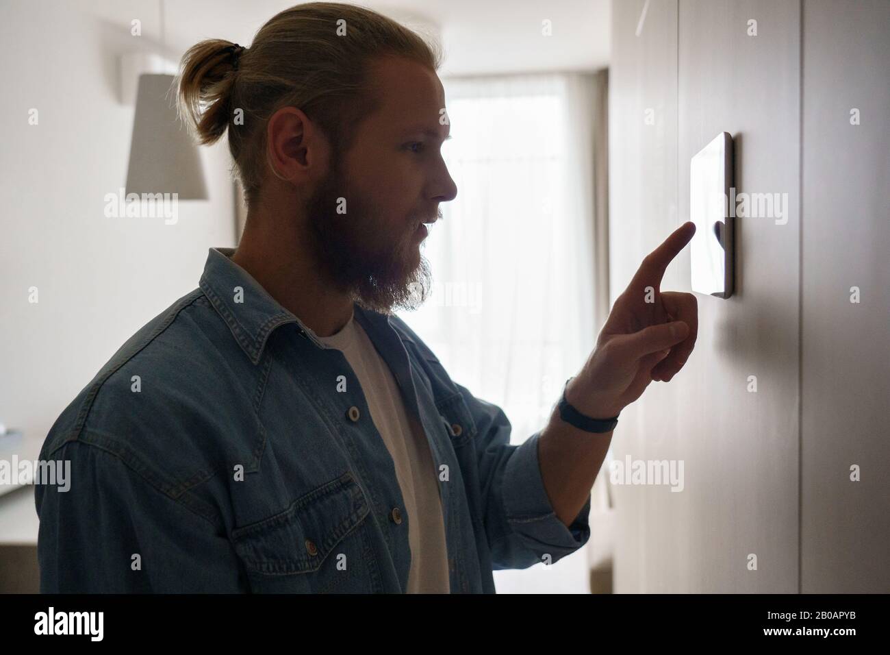Young man using smart home touch screen technology device on wall Stock Photo