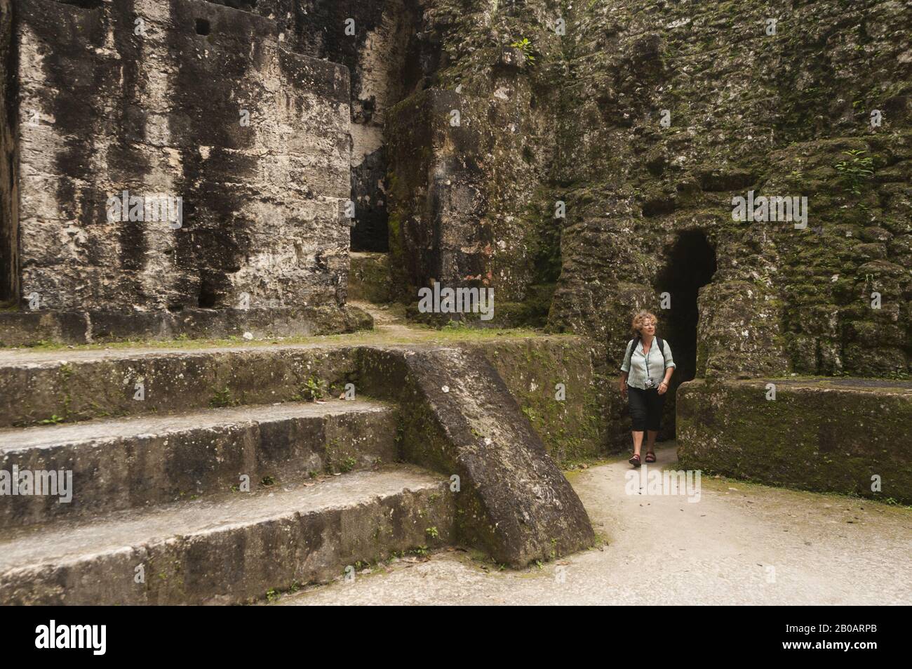 Guatemala, Tikal National Park, Central Acropolis, woman exiting ruins; UNESCO World Heritage Site Stock Photo