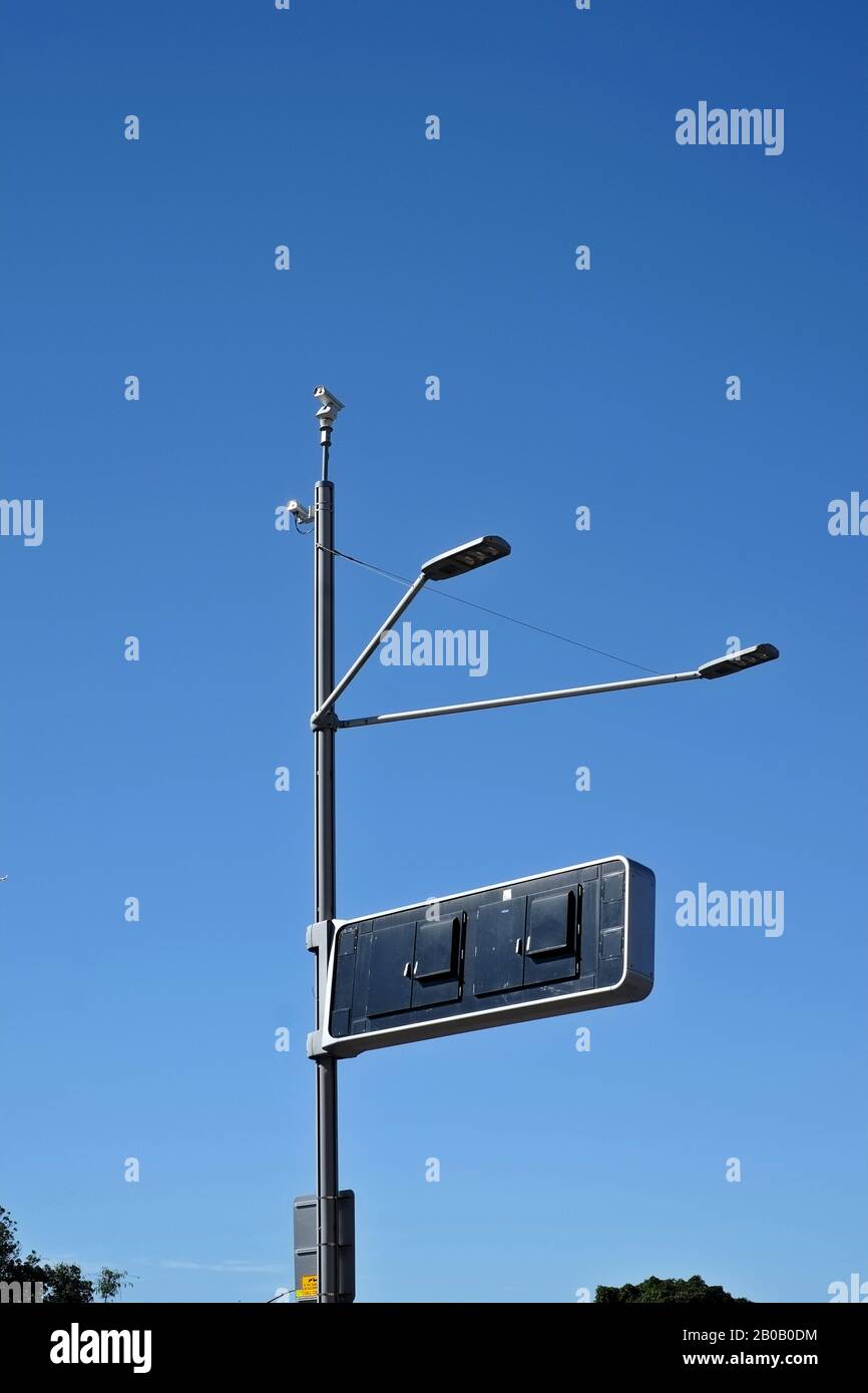 Security camera on a highway light pole, a clear blue sky, like a stick insect, two lights a rectangular information sign, street surveillance Stock Photo