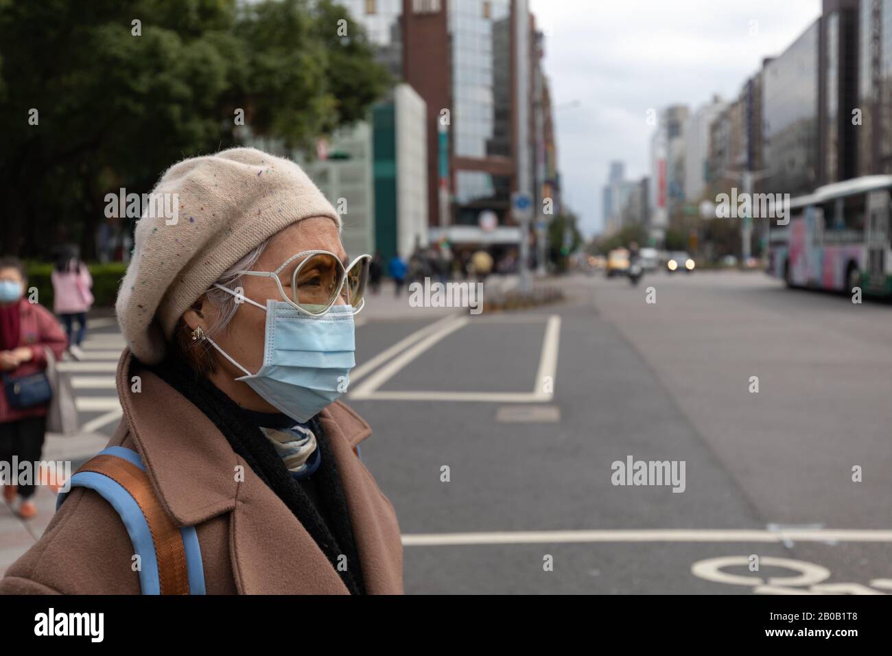 Taiwanese woman on busy Taipei street wearing face mask to protect herself against the covid-19 coronavirus epidemic. Stock Photo