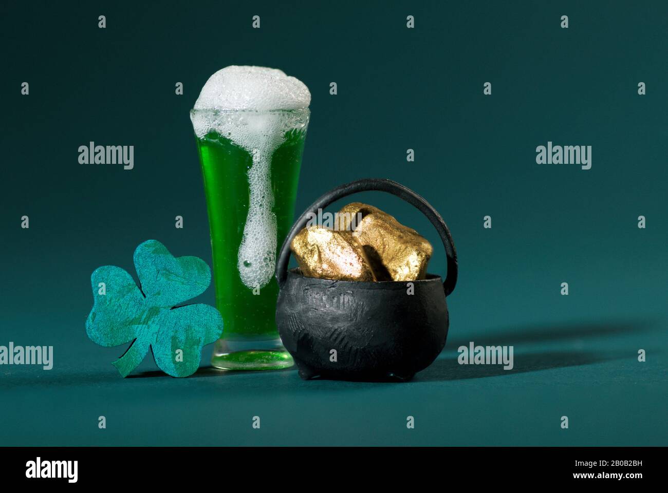 Green Pint of Beer, Shamrock and Pot of Gold on Turquoise Background Stock Photo