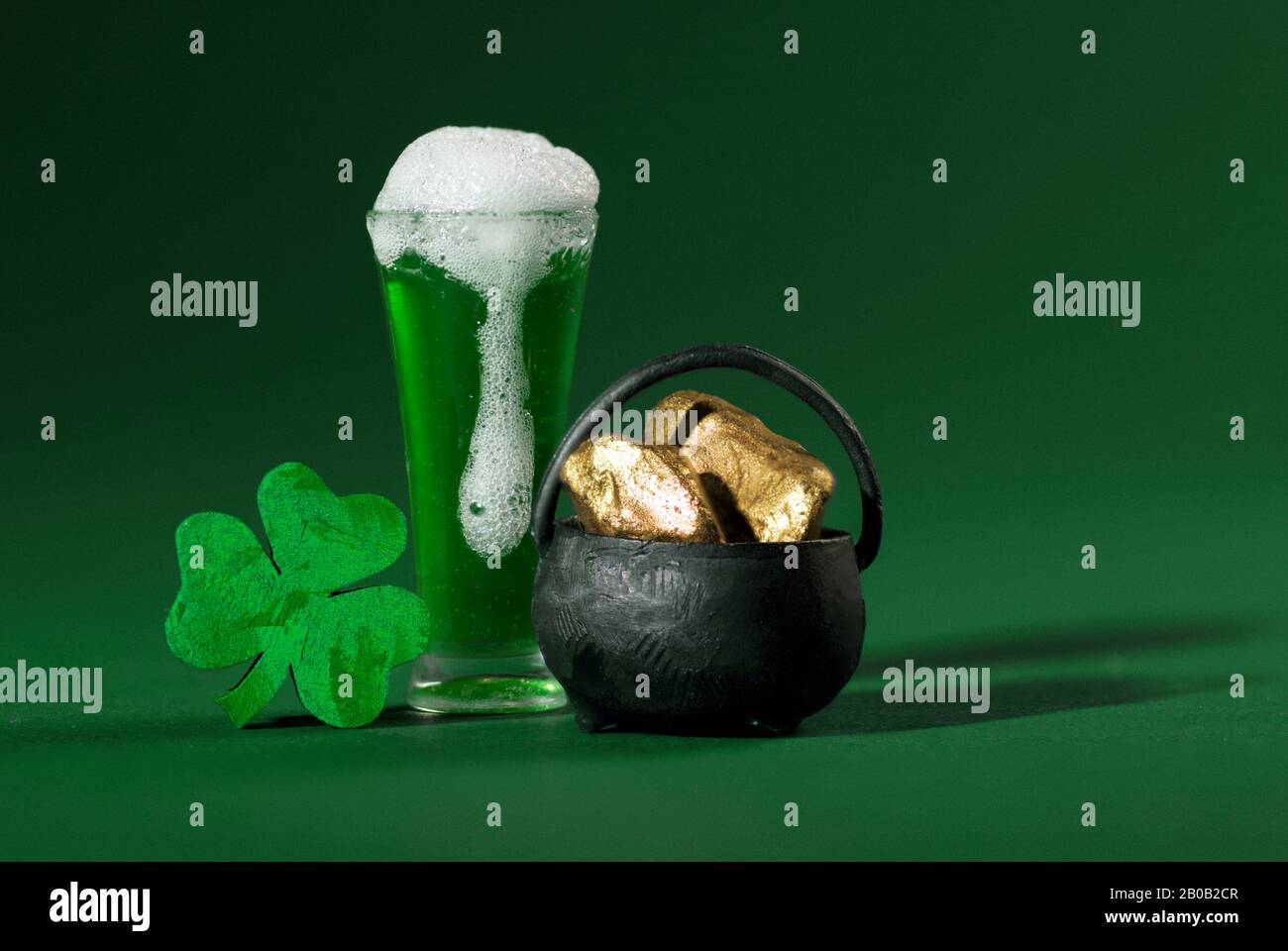 Green Pint of Beer, Shamrock and Pot of Gold on Green Background Stock Photo