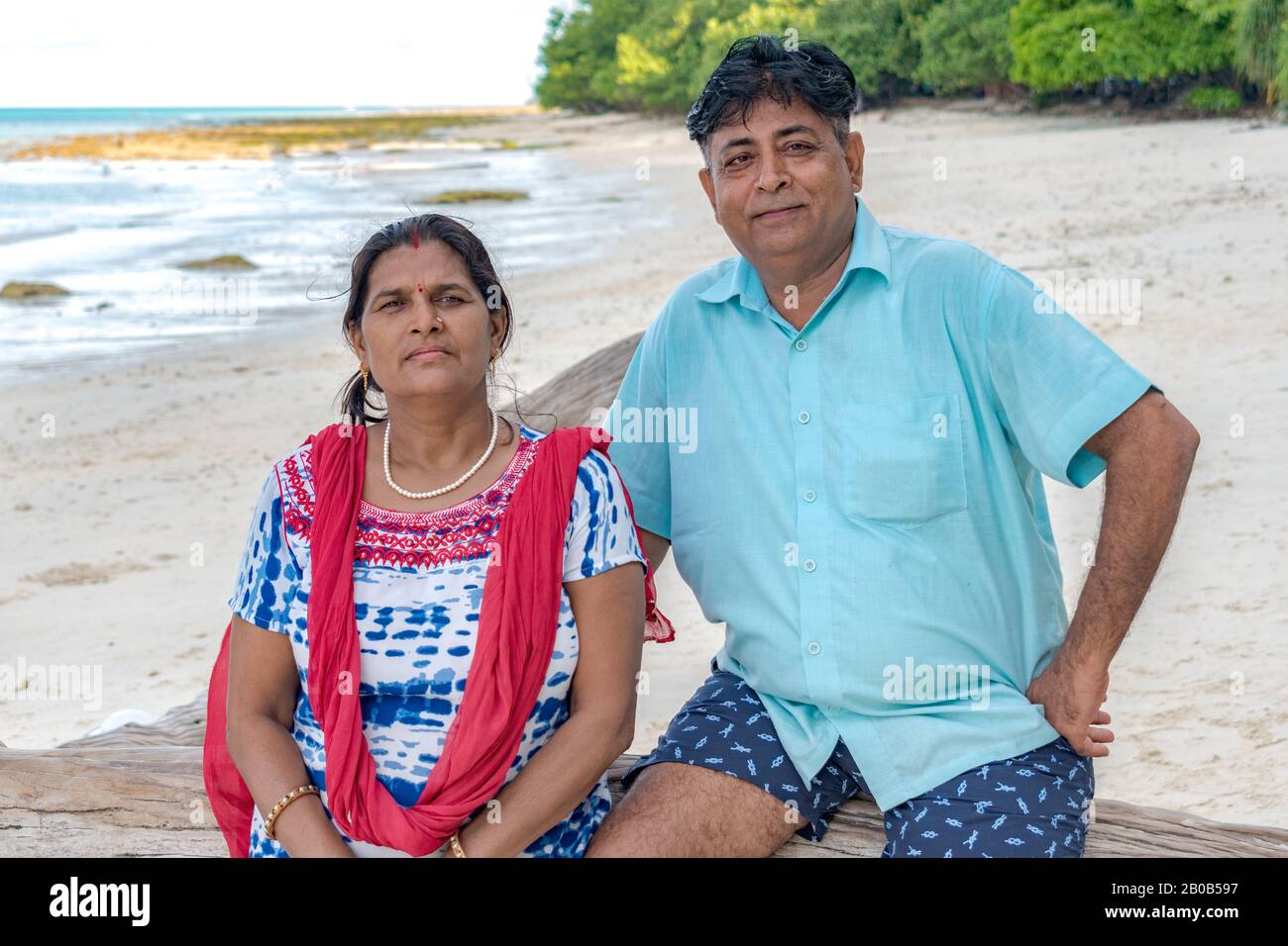 Beautiful photo of happy, middle aged Indian couple spending holidays at tropical island. Female wearing ethnic Indian attire and male in casual. Stock Photo