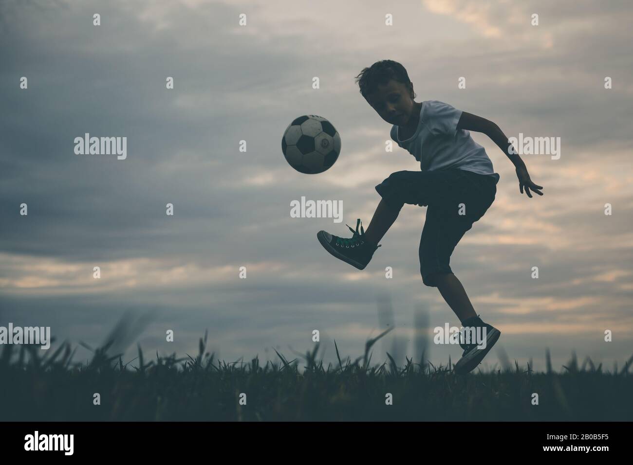 Young little boy playing in the field  with soccer ball. Concept of sport. Stock Photo