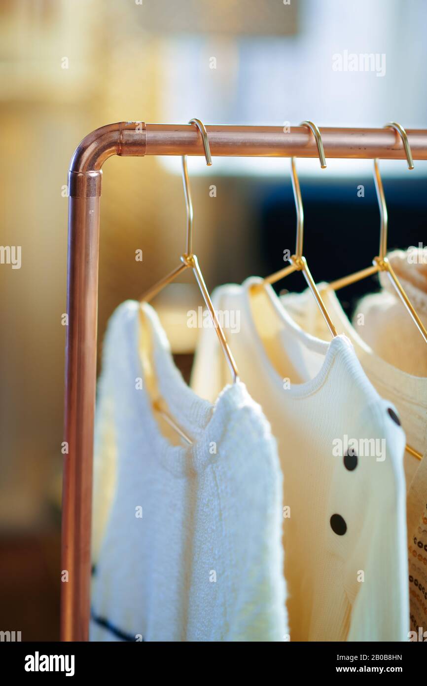 Closeup on modern copper clothes rack with clothes on hangers Stock