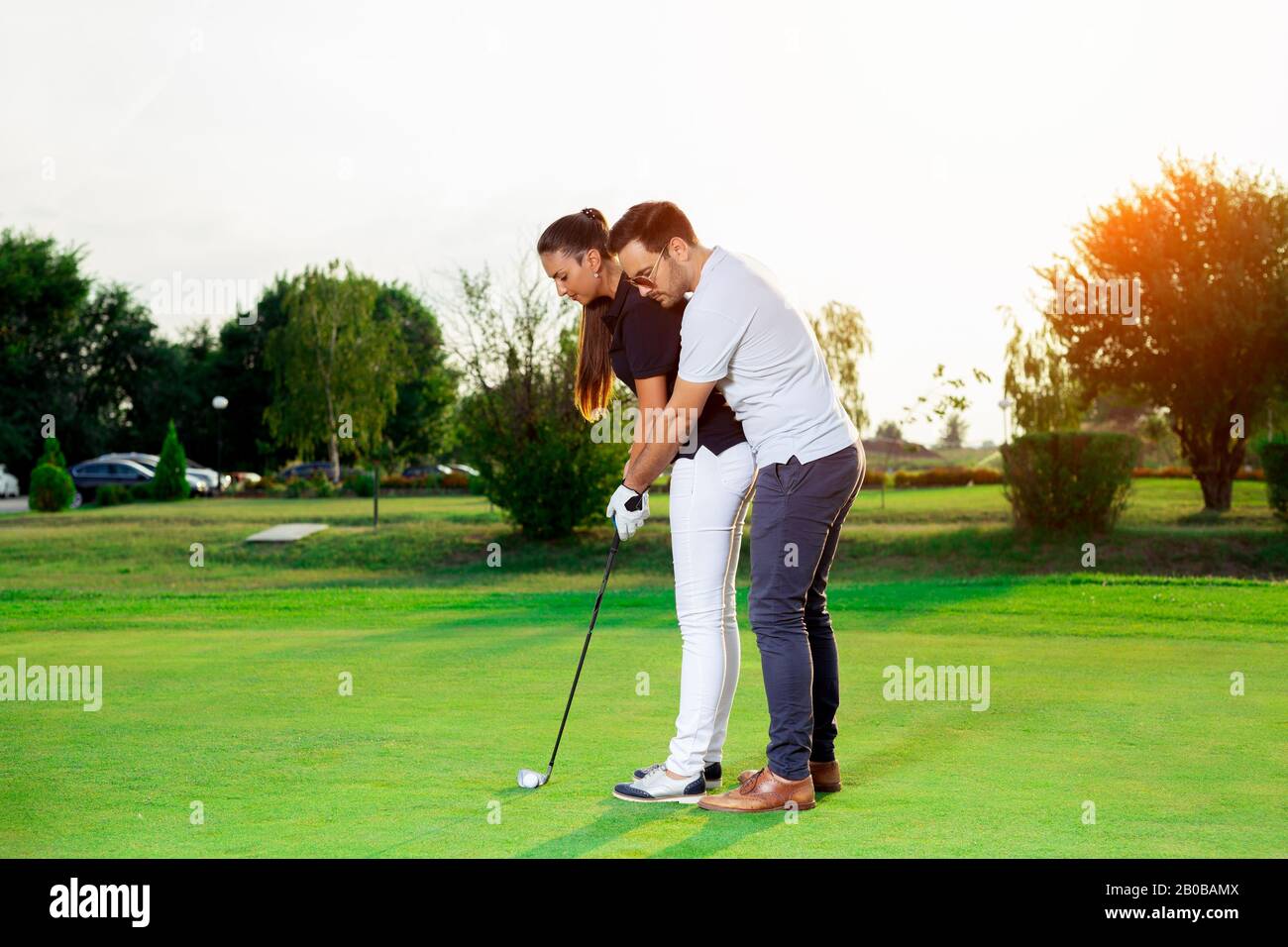 Handsome Husband Is Teaching His Lovely Wife How To Play Golf Stock