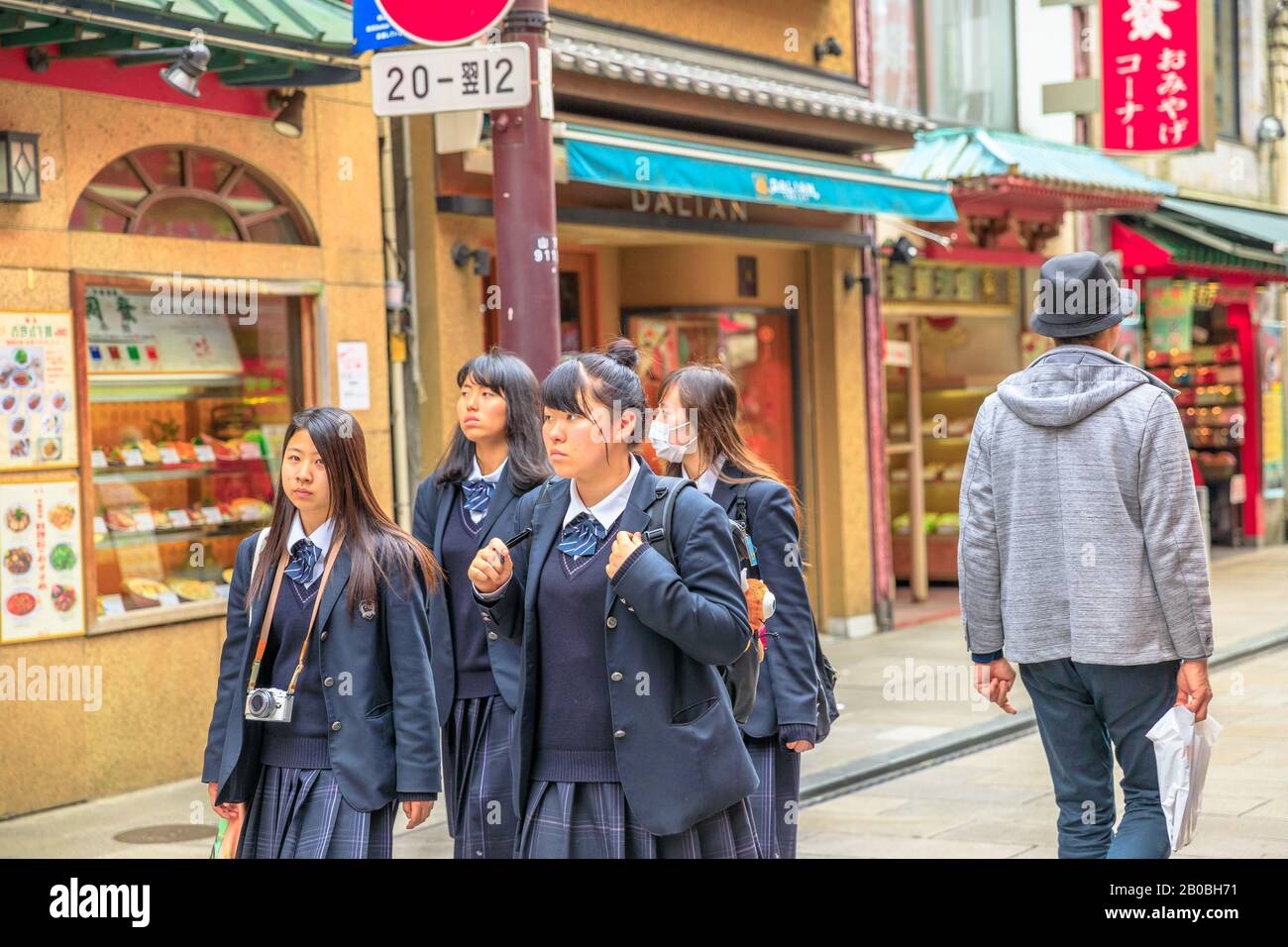 Yokohama, Japan - April 21, 2017: group of asian girls in school uniform wear a mask while walking in the heart of Yokohama Chinatown, the Japan's Stock Photo