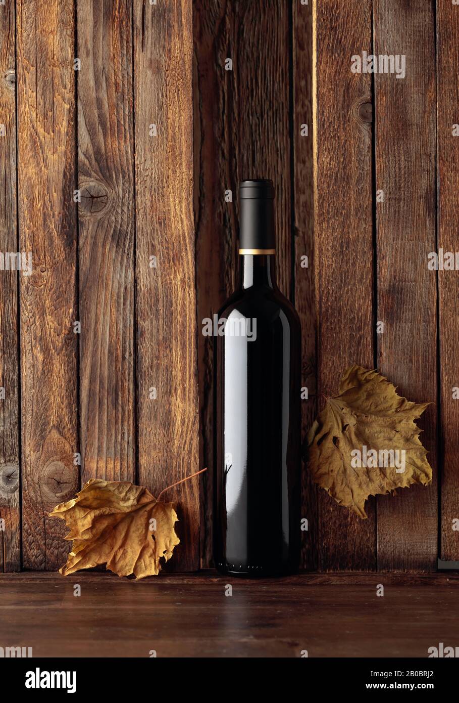 Bottle of red wine and dried vine leaves on a old wooden background ...