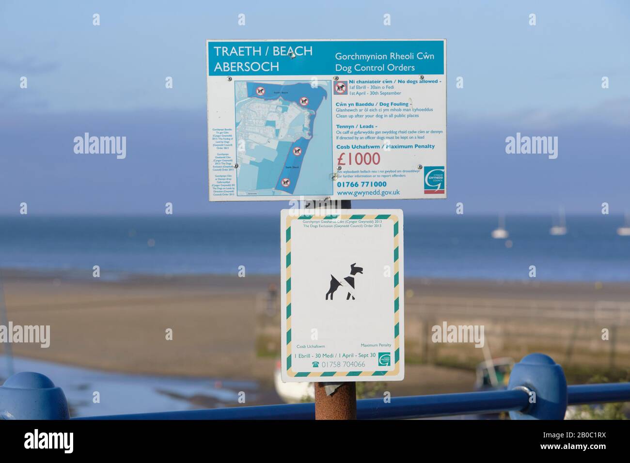 Traeth beach abersoch dog control order sign mounted on pole, with soft focus blurred sea and