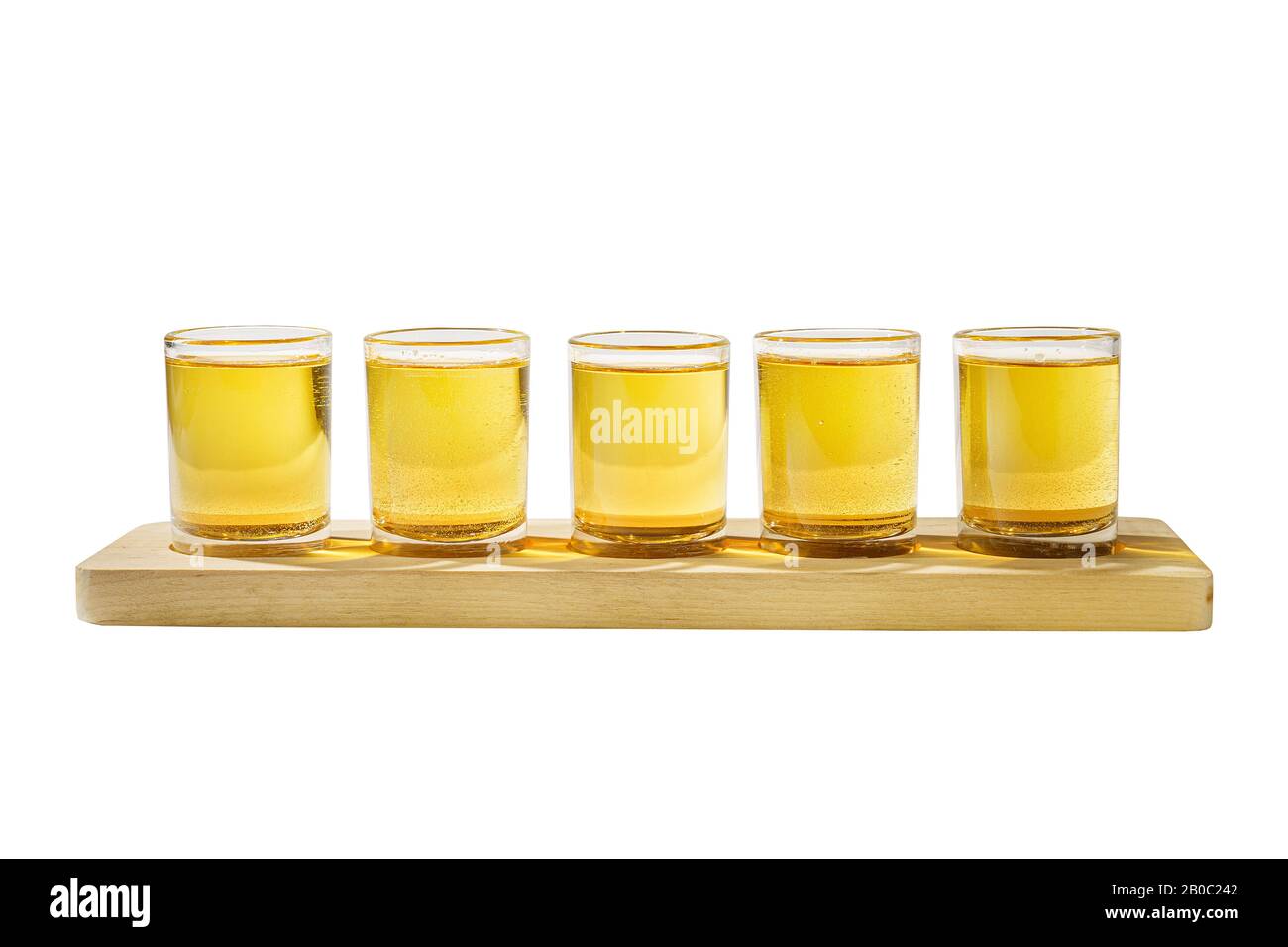 Yellow, same color opaque cocktails, a set of shots in one row, five servings on a wooden stand, substrate, side view Isolated white background. Drink Stock Photo