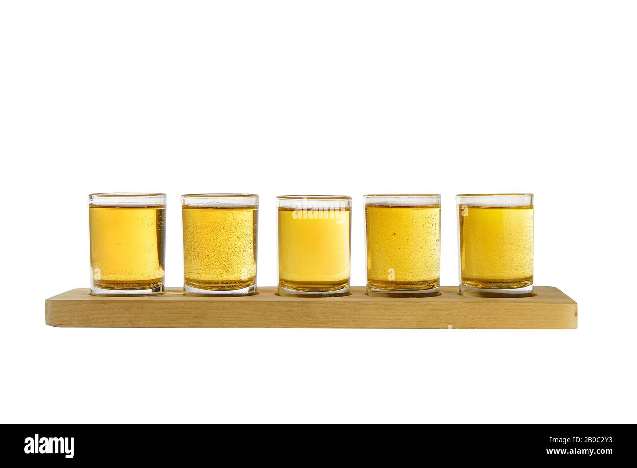 Yellow, same color opaque carbonated cocktails, a set of shots in one row, five servings on a wooden stand, substrate, Side view Isolated white backgr Stock Photo