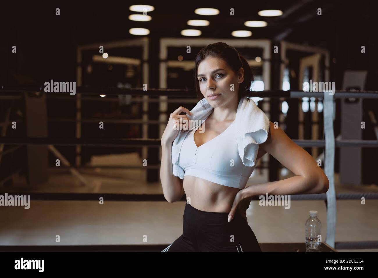 Smiling fit girl holding towel and taking rest in gym Stock Photo - Alamy