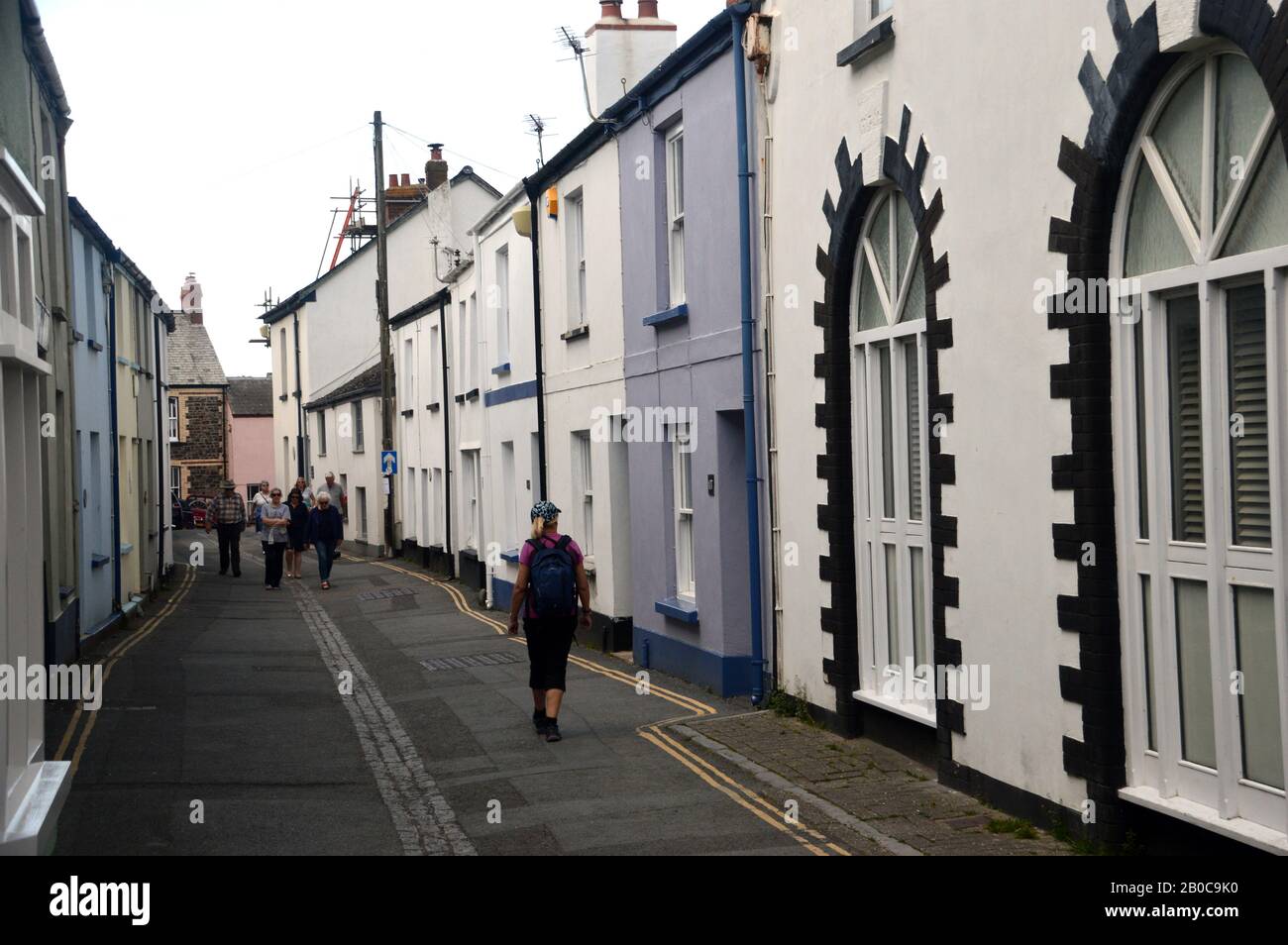 Woman Hiker Walking through Irsha Street a Street of Pastel Coloured Terraced Houses in Appledore on the South West Coast Path, North Devon. Stock Photo