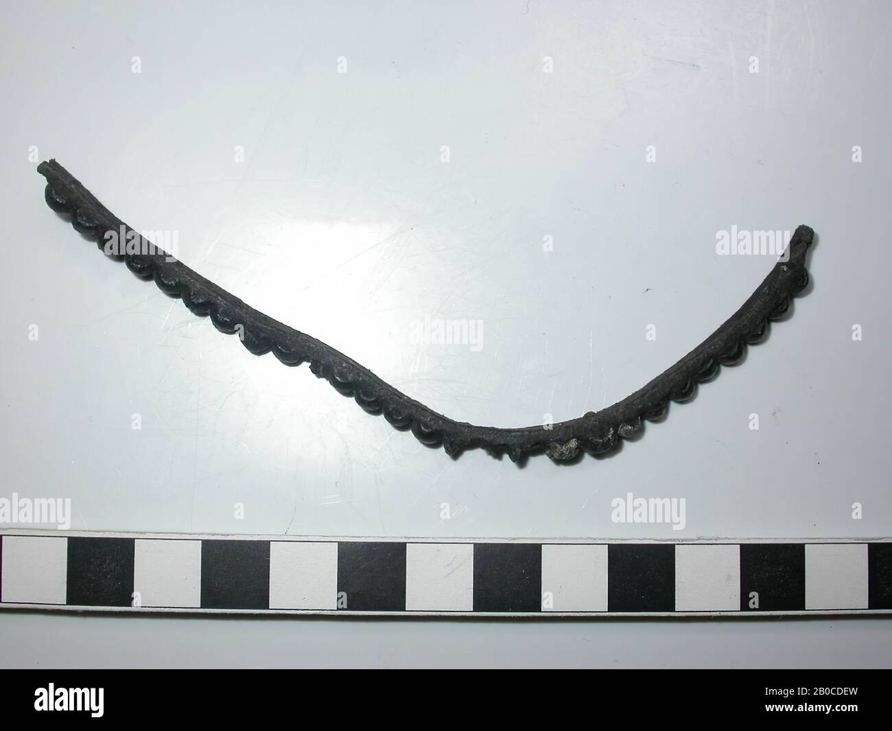 Fragment leather belt with fittings (copper alloy). On the belt are 24 decorative nails with round and round cap and 2 nails without cap. 2 nails with cap are completely missing. Three caps are incomplete. The color of the batter is dark gray to black because of the corrosion of the lead. There is no space between the caps and the fittings are as wide as the leather. The diameter of the batter is 0.45 cm and the thickness is 0.3 cm. The diameter of the nails is 0.1 cm., Belt with fittings, organic, leather, metal, copper alloy and lead, Belt: L: 13.7 cm, W: 0.45 cm, D: 0.25 cm, end 14th Stock Photo