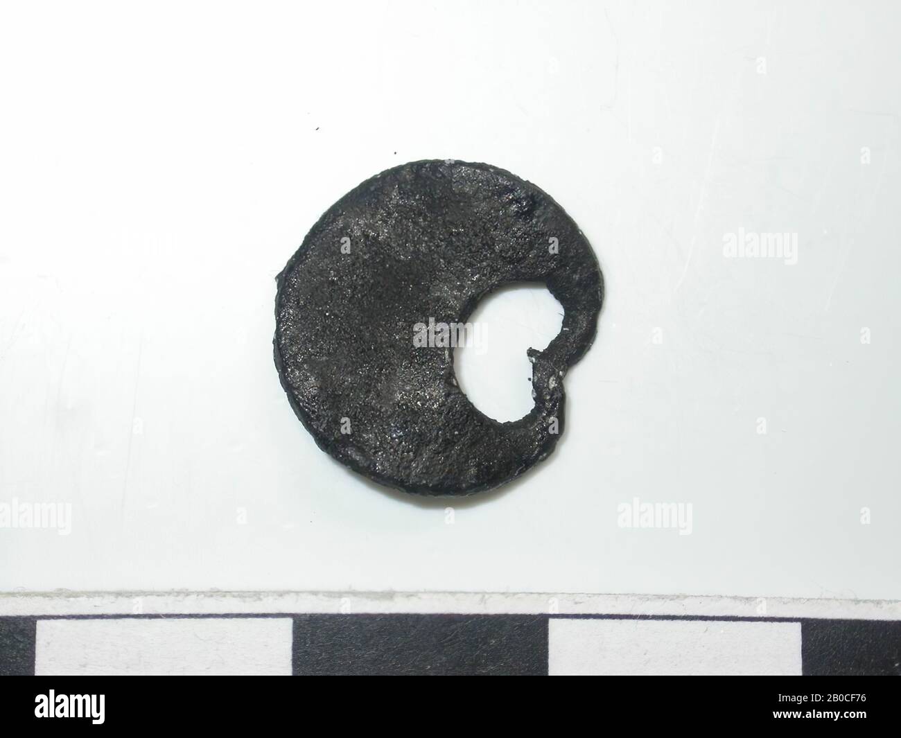 Half moon, golden with dark spots. Flat crescent, with the ends together. Back is flat and has a seam. 1 pin attachment. Pin is not measurable., Belt stroke, metal, copper alloy, L: 1,4 cm, W: 1,3 cm, D: 0,1 cm, end of the 14th century 1350-1400, Netherlands, Zeeland, Holly, Verdronken Land Stock Photo