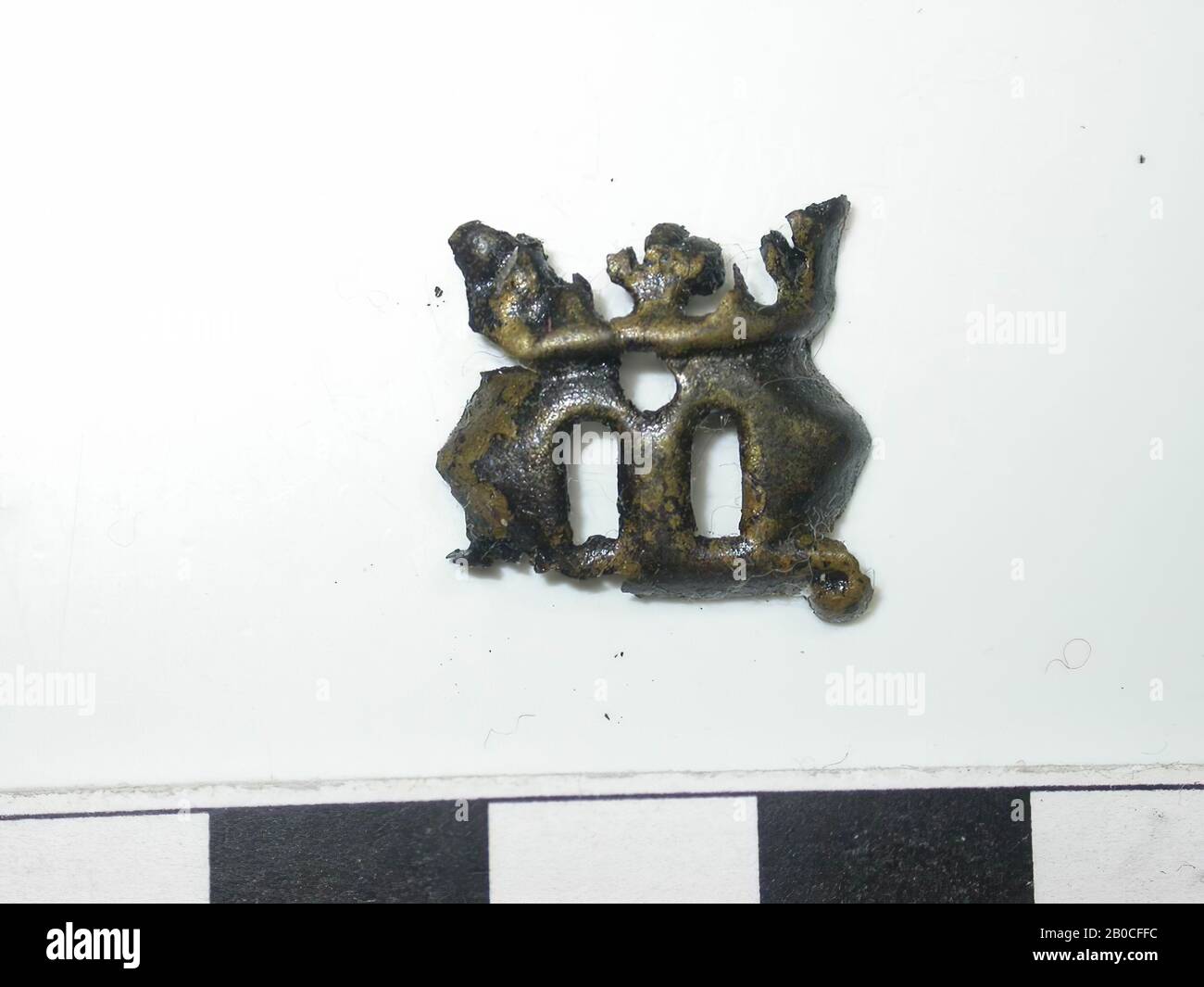 Letter M, gold (copper alloy). Letter M. There is a crown on top of the letter. Bottom is damaged. There is a hole under the crown. Back is hollow. No confirmation visible., Belt stroke, metal, copper alloy, H: 1.65 cm, W: 1.65 cm, D: 0.05 cm, end of the 14th century 1350-1400, The Netherlands, Zeeland, Hulst, Verdronken Land Stock Photo