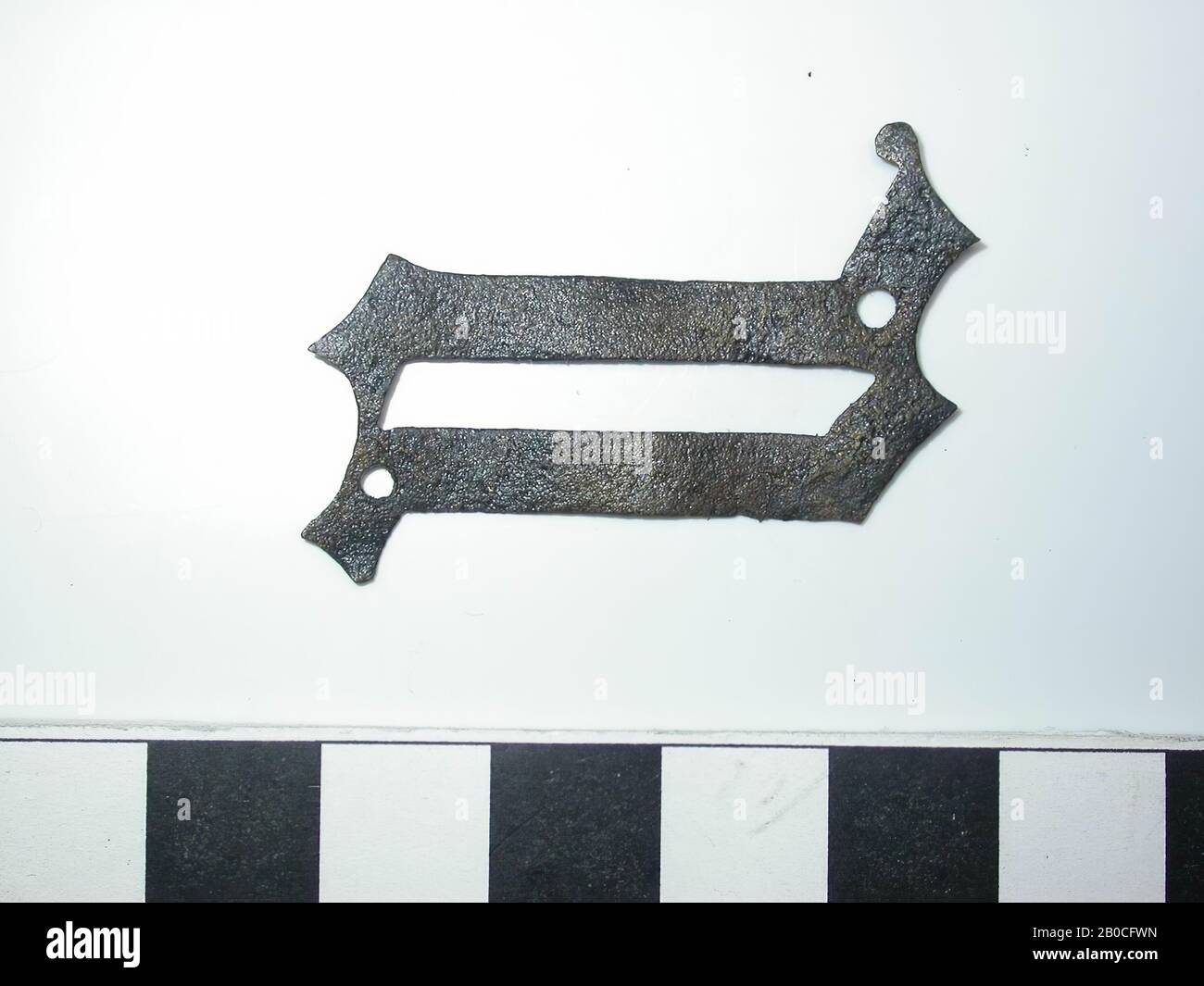 Letter Q, dark with gold-colored spots (copper alloy). Letter Q with 2 small round holes for the pin. Back is flat. No attachment is visible., Belt fitting, metal, copper alloy, H: 4.1 cm, W: 2.8 cm, D: 0.1 cm, end of the 14th century 1350-1400, The Netherlands, Zeeland, Hulst, Verdronken Land Stock Photo