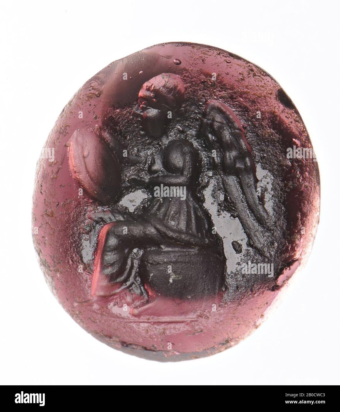 Vz: the goddess is dressed in a chiton with long cover (apoptygma) and sits on a throne with lions' legs, she has a round shield on her knees with her right hand and writes on it with her left hand., Gem, intaglio , glass paste, Color: brown, Shape: oval, Machined: Maaskant-Kleibrink, M., Catalog of the engraved gems in the Royal Coin Cabinet, 1978, p.60, fig.2, type 3C, front convex, Type: body modeling with rounded drills, details not clear, 13 x 12 mm, D. 5.5 mm, 2nd century BC. -200 Stock Photo