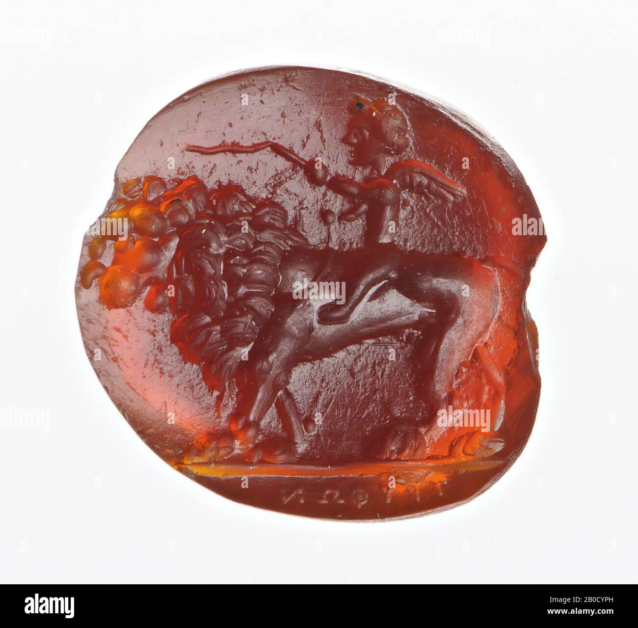 Vz: a small Cupid with his hair rolled around his relatively large head, in his left hand he has a whip and in the other the reins of a big lion, the lion has large curly mane and an open mouth. gem, intaglio, ringstone, carnelian, Color: dark red, Shape: oval, Machining: front very slightly convex, Method: deep modeling with large rounded drills, detailing with short thick rounded wheel grooves., 12.5 x 11.5 mm, D. 3 mm, Roman imperial age, 1st century AD. 1-100 AD Stock Photo