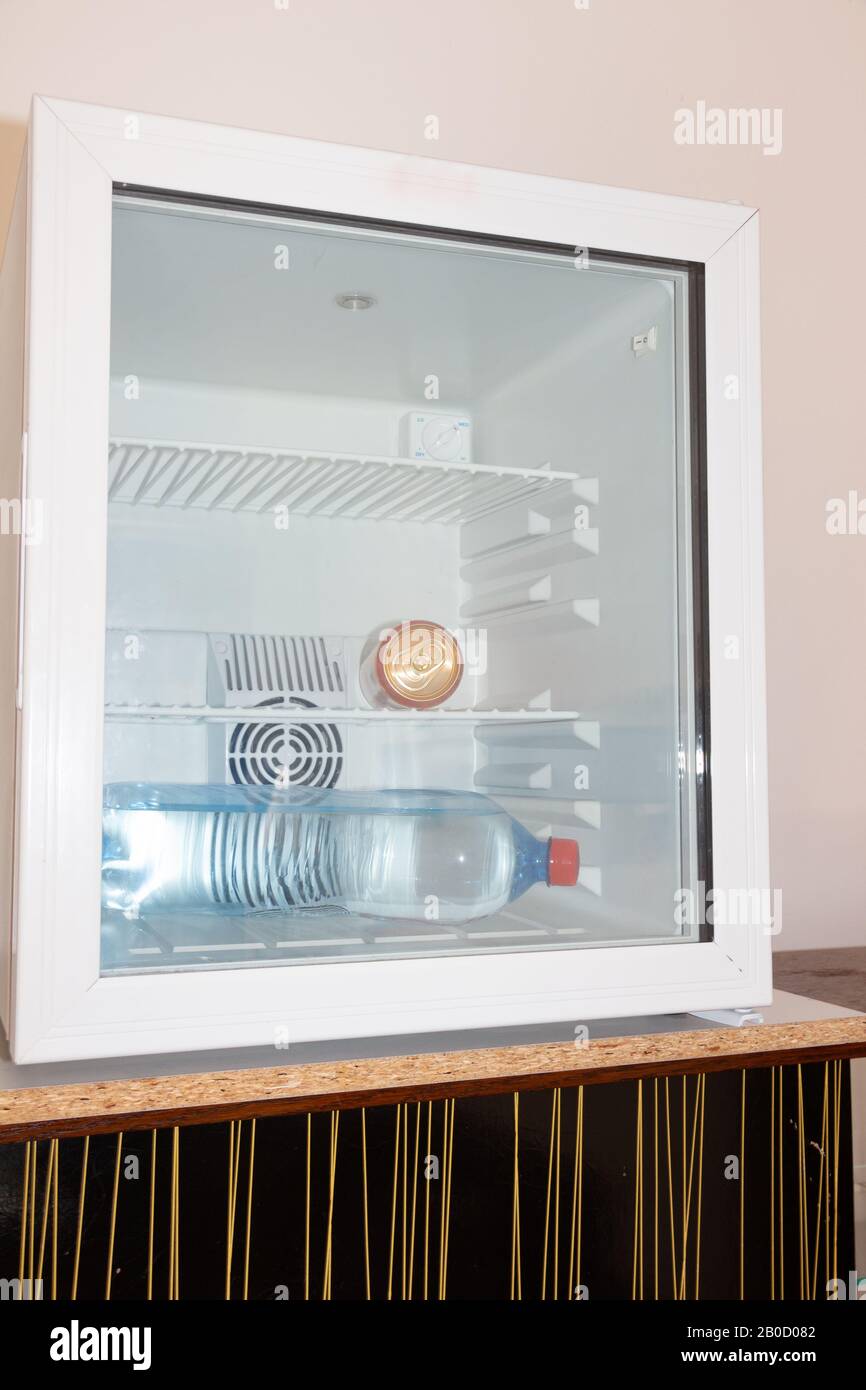 Can and water bottle in a minifridge in the room of an hotel Stock